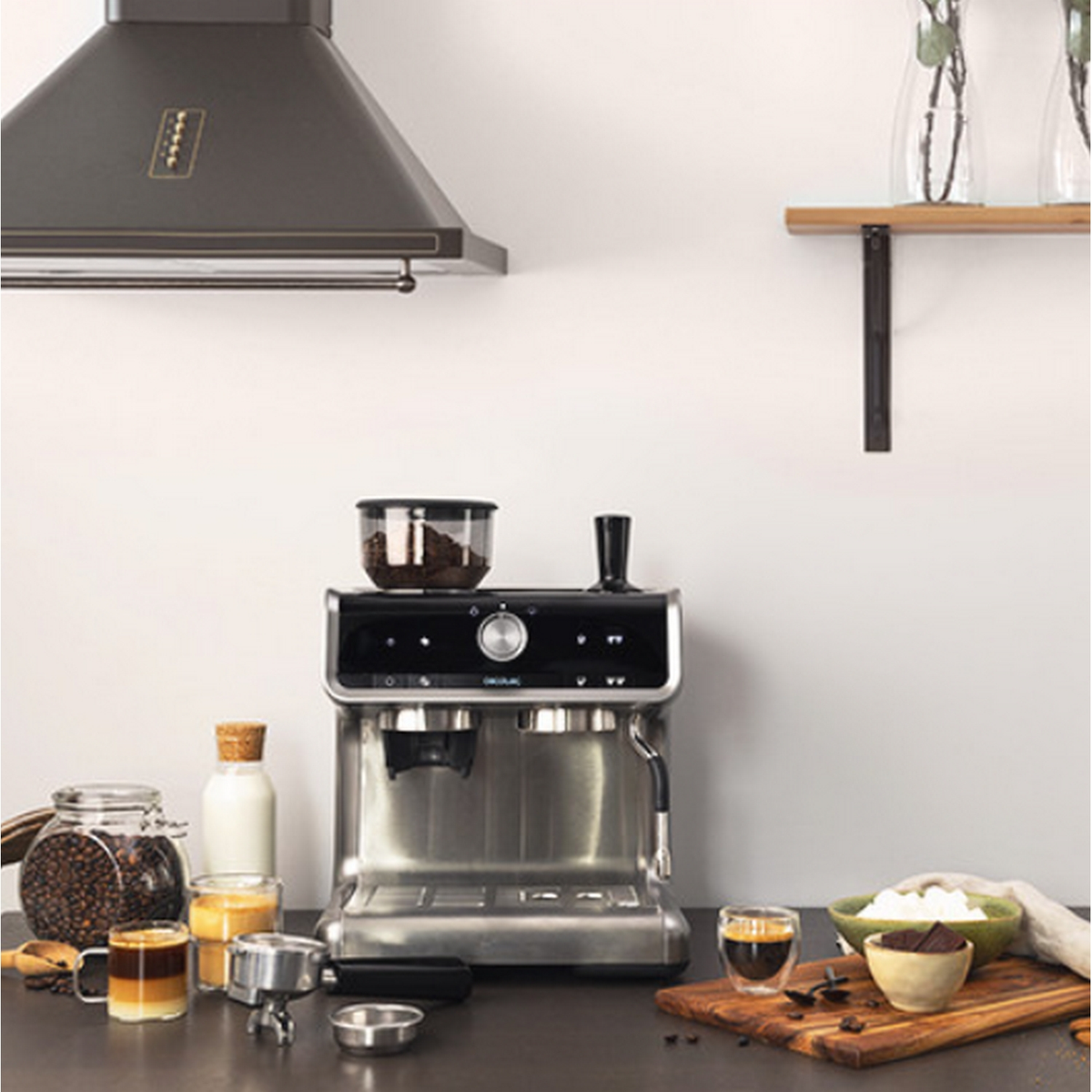 Macchina per espresso con chicchi di caffè, latte e cioccolato. Una scena di cucina con cappa e mensola.