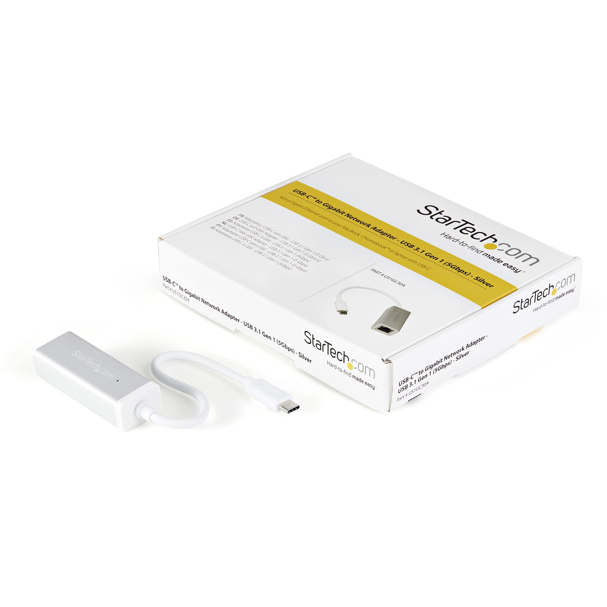 Una caja blanca y un adaptador plateado con cable USB-C sobre una superficie blanca. La caja tiene texto.