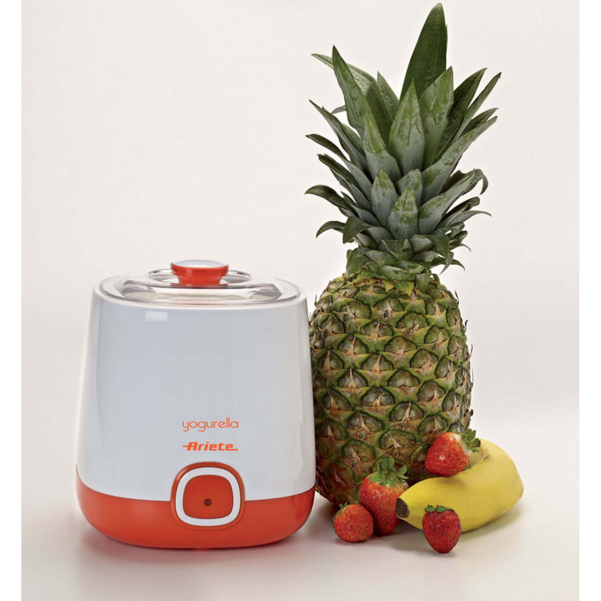 Biało-pomarańczowy jogurtownica, ananas, truskawki i banan na białej powierzchni.