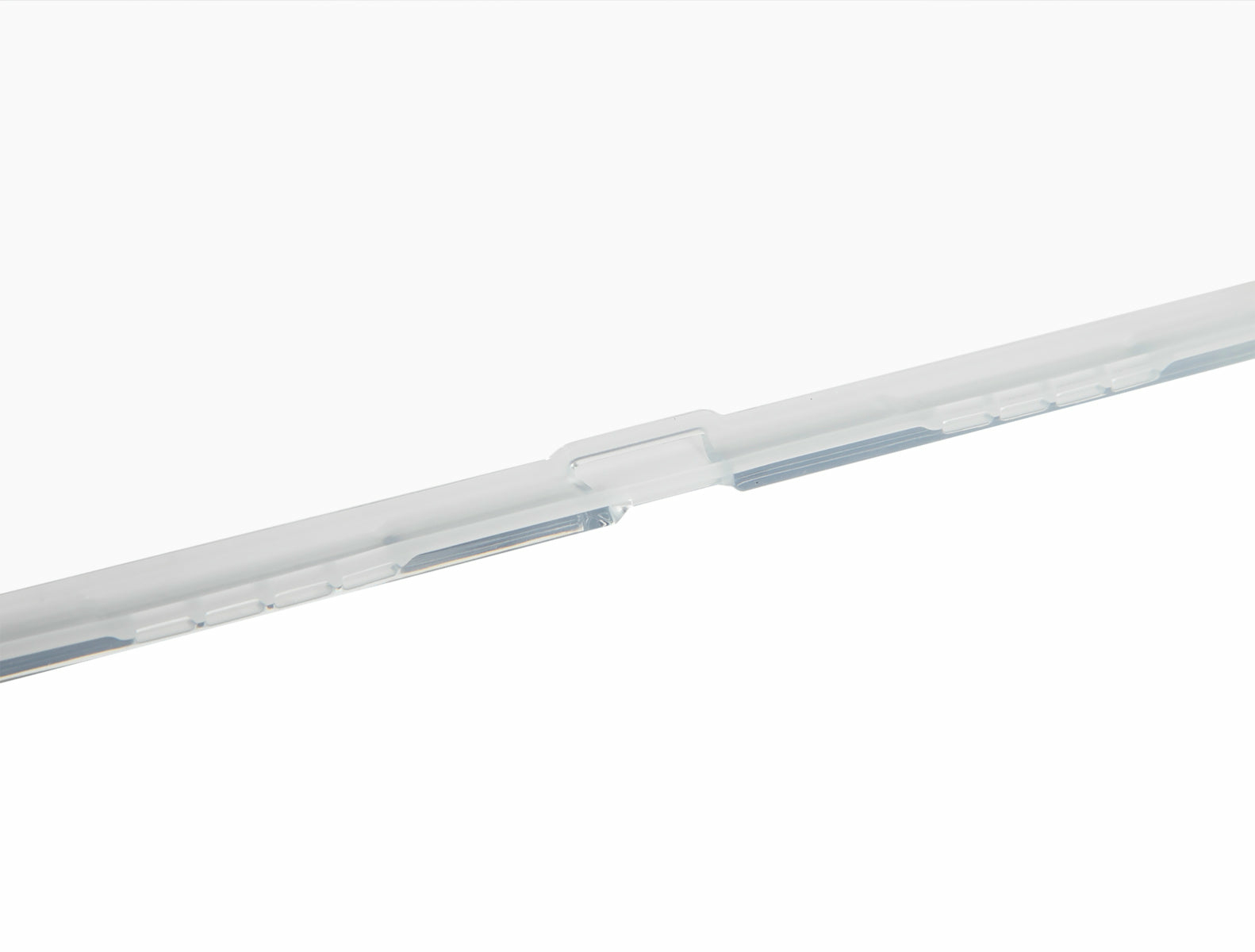 Una tira de plástico transparente con muescas rectangulares. El fondo es blanco liso.