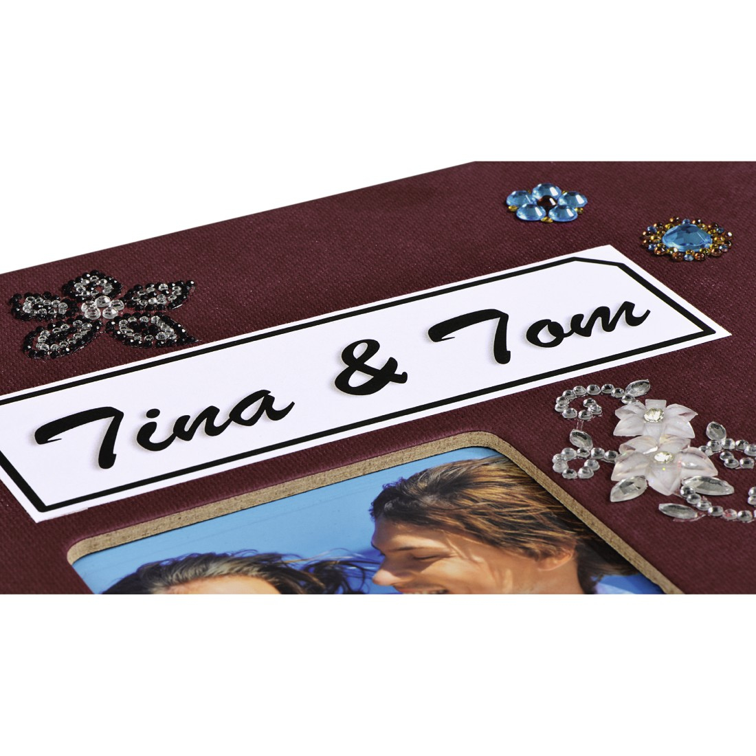 Ramka na zdjęcia z napisem 'Tina & Tom'. Zawiera zdjęcie pary. Ozdobiona kwiatowymi zdobieniami i biżuterią na bordowym tle.