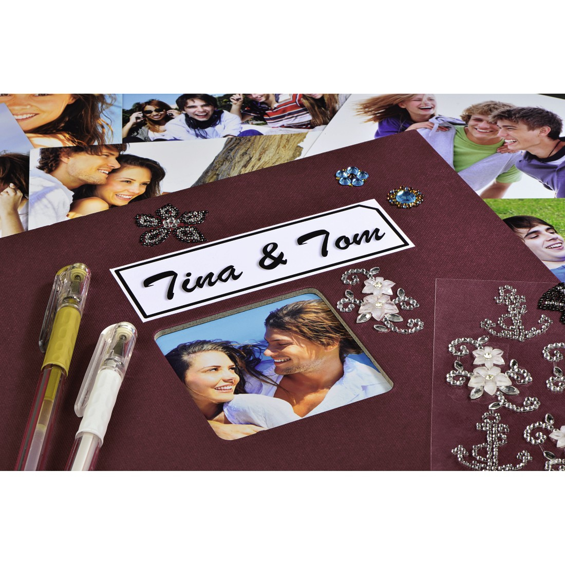 Album z zdjęciami, długopisami i ozdobami. Widoczny tytuł 'Tina & Tom'. Zdjęcia uśmiechniętych ludzi w tle.