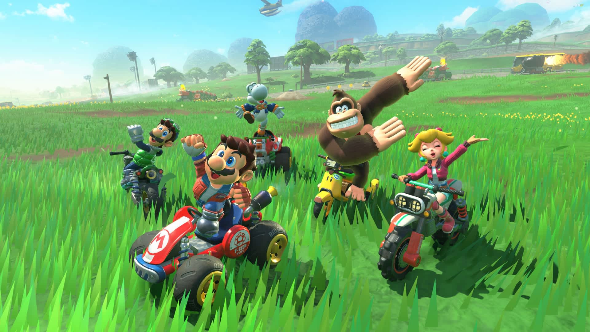 Postacie z Mario Kart ścigają się na gokartach i motocyklach po trawiastym polu. Donkey Kong macha. Obecni są także Peach, Luigi i Yoshi.