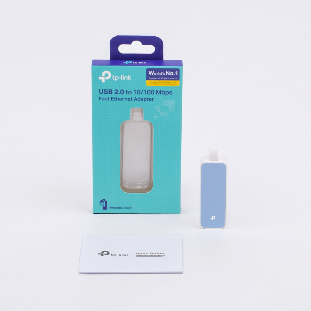 Adapter Ethernet USB TP-Link, pudełko i instrukcja obsługi na białej powierzchni. Adapter jest jasnoniebieski.