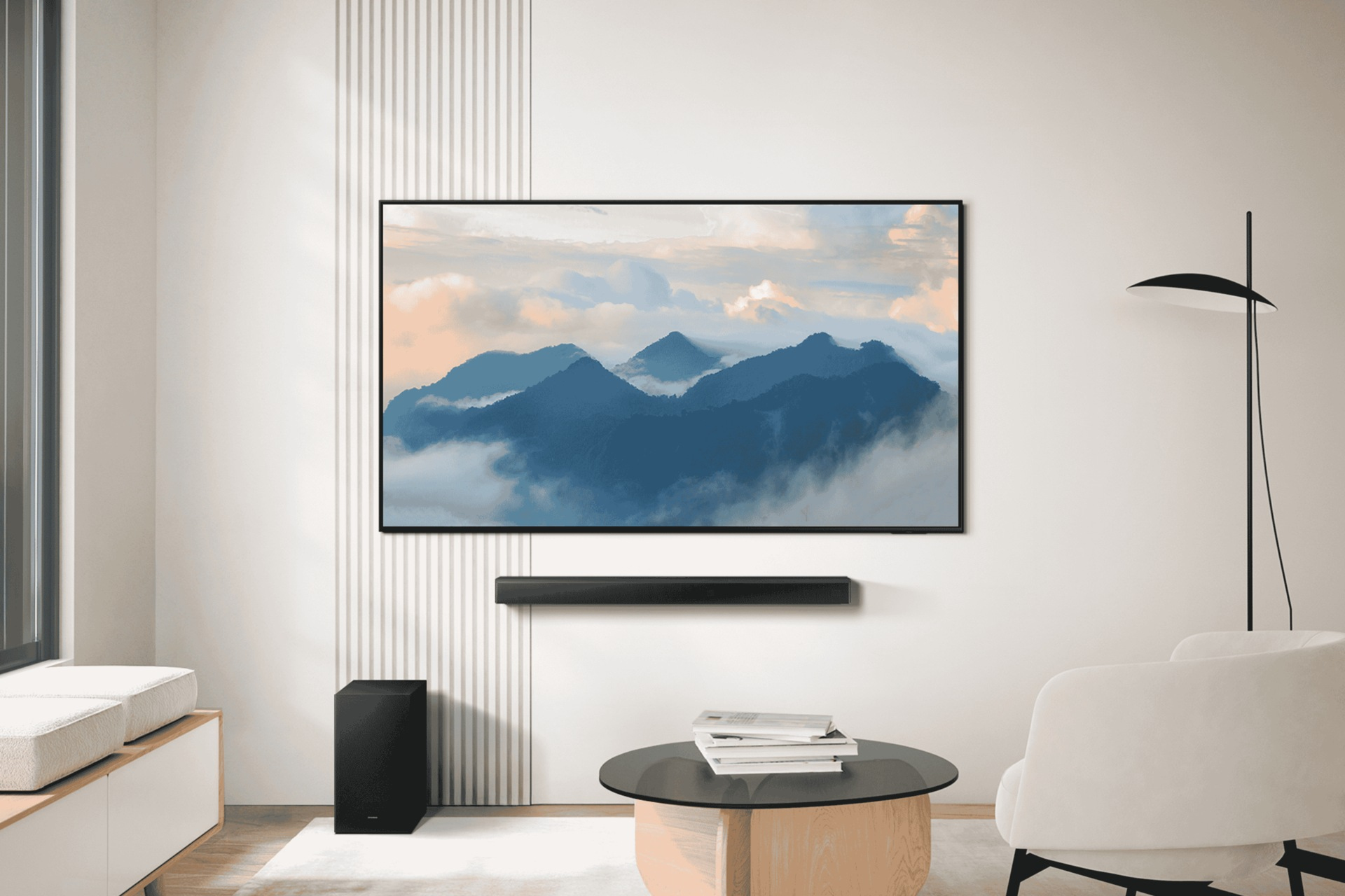 Wohnzimmerszene mit Fernseher, der Bergkunst zeigt, Soundbar, schwarzem Subwoofer, rundem Tisch, weißem Stuhl und Stehlampe.