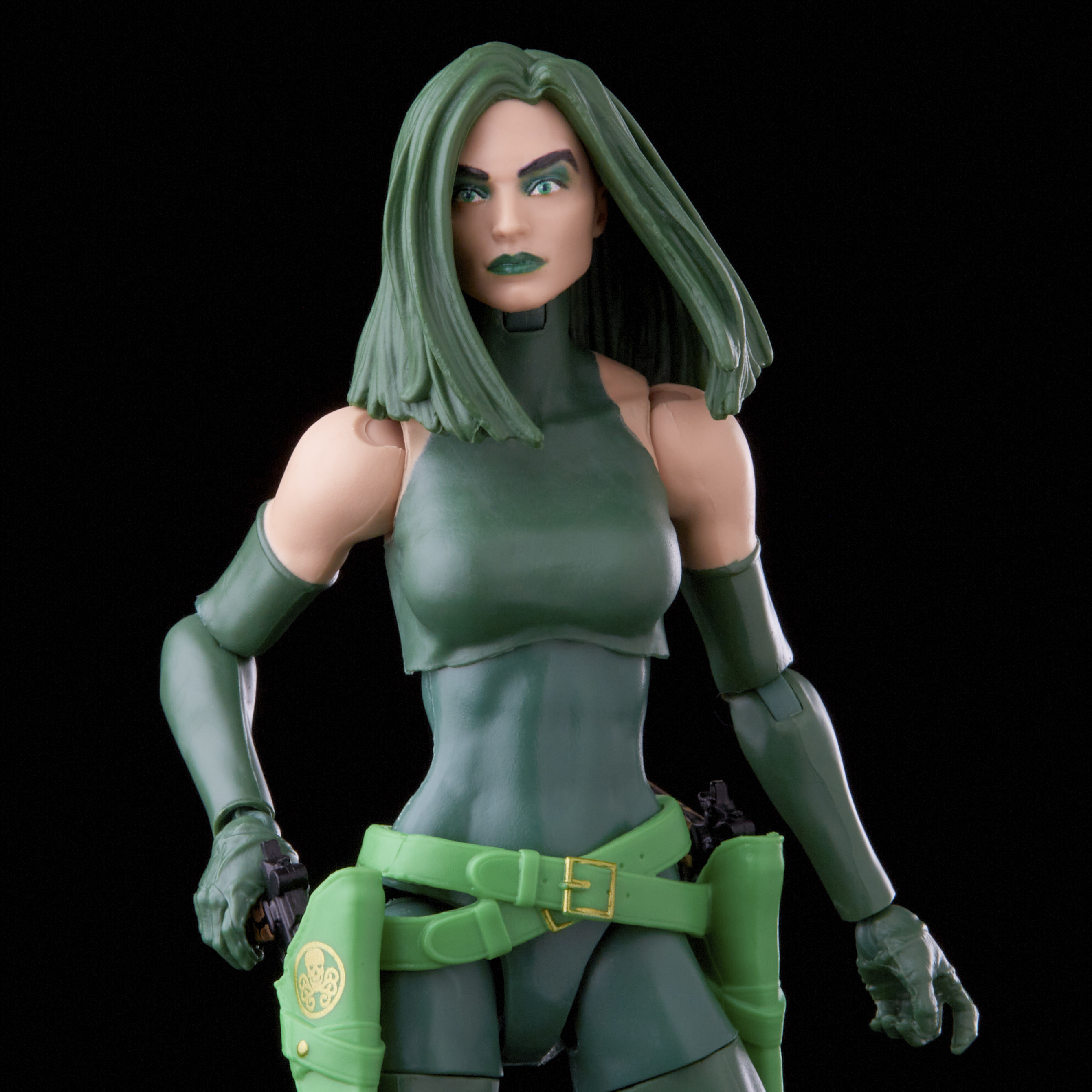 Una figura de acción de piel verde, con cabello y atuendo verdes, sosteniendo una pistola. Fondo negro.