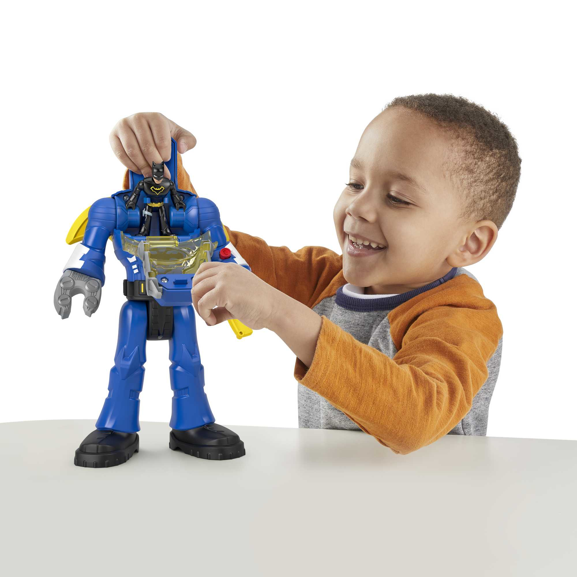 Een lachende jongen speelt met een blauw robotspeelgoed met een klein Batman-figuur erin. De achtergrond is wit.