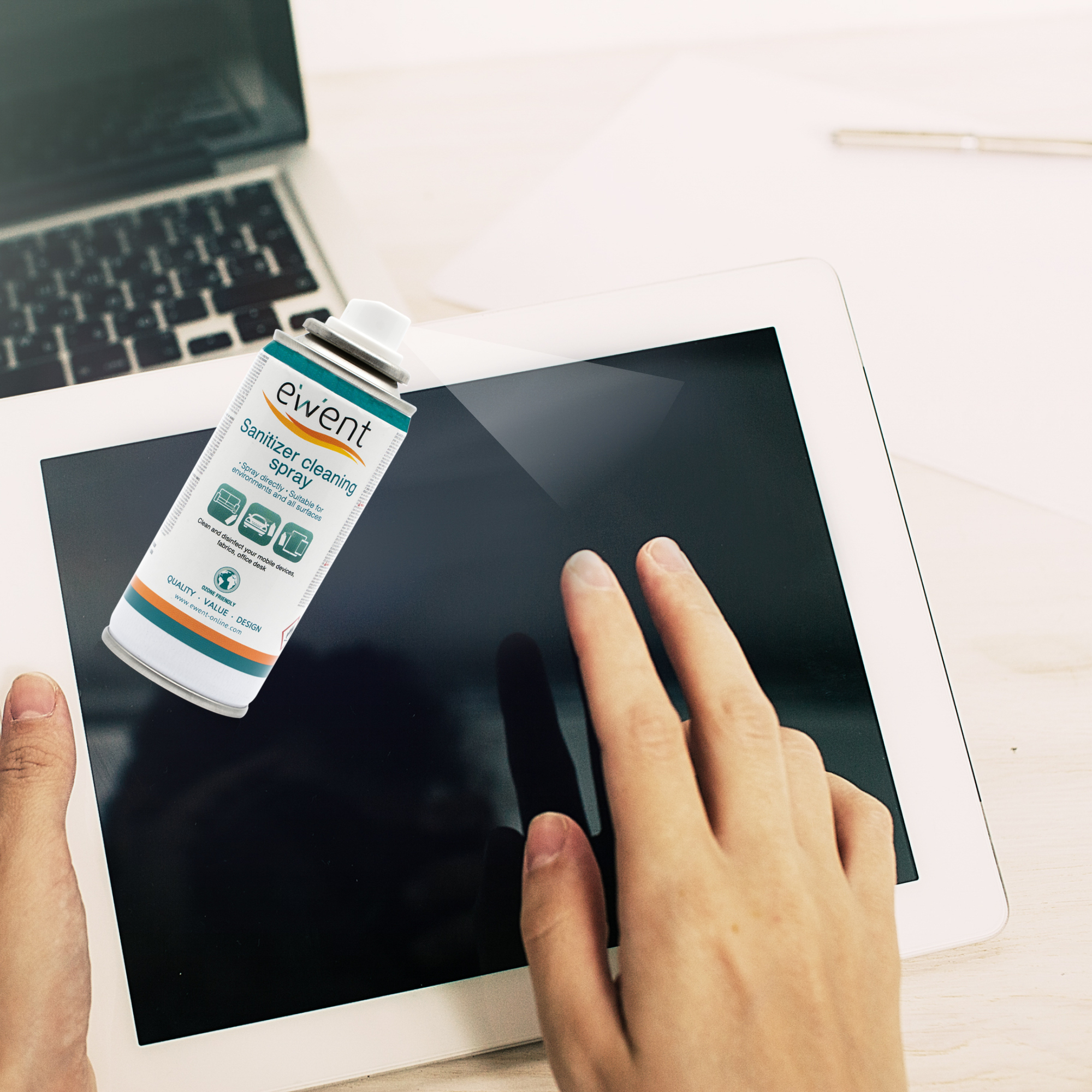 Ręka dotyka ekranu tabletu. Puszka ze sprayem dezynfekującym znajduje się nad tabletem. Laptop jest w tle.