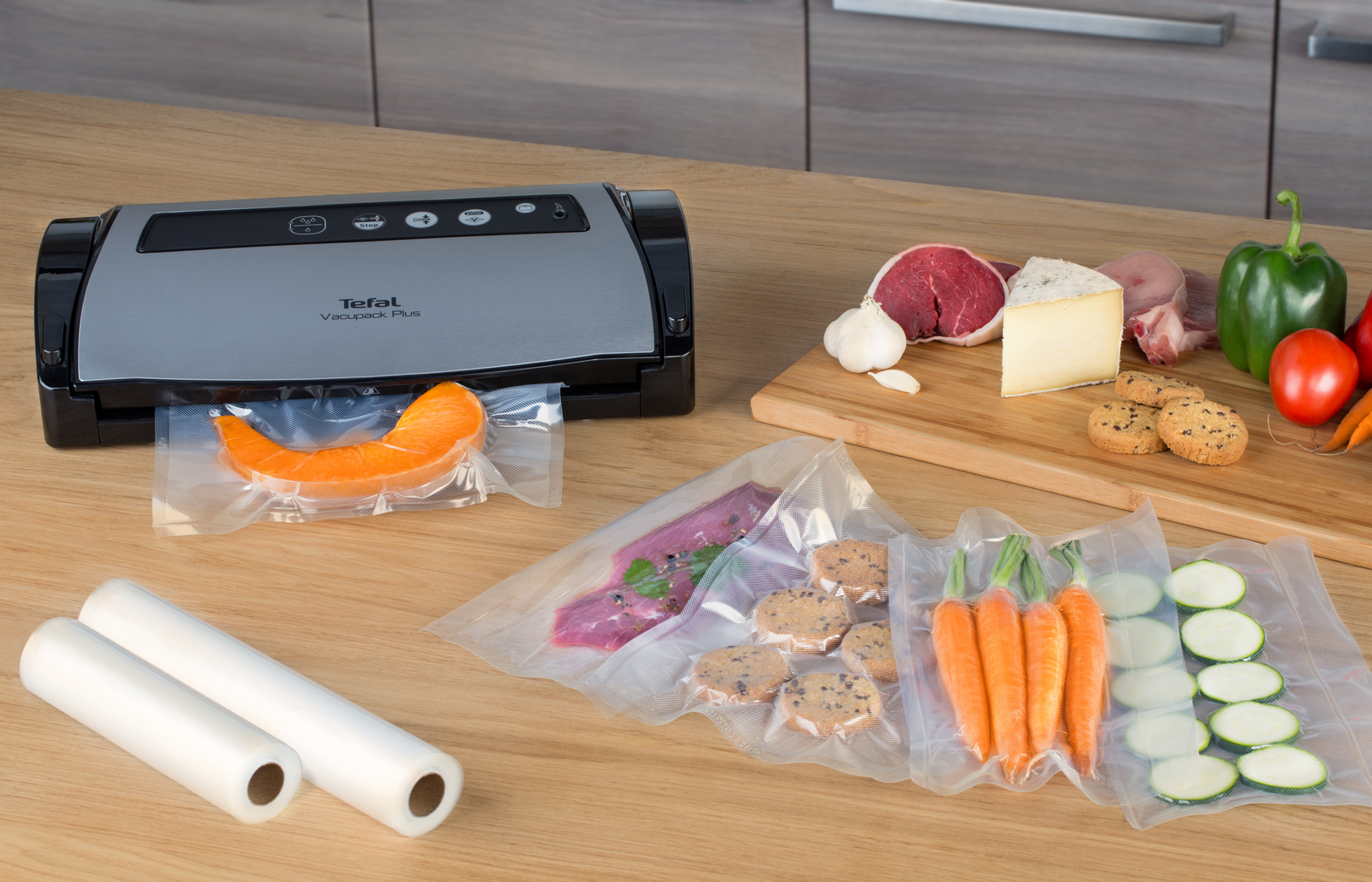 Zgrzewarka próżniowa z produktami spożywczymi, takimi jak mięso, warzywa i ciastka, wszystko w zamkniętych workach.