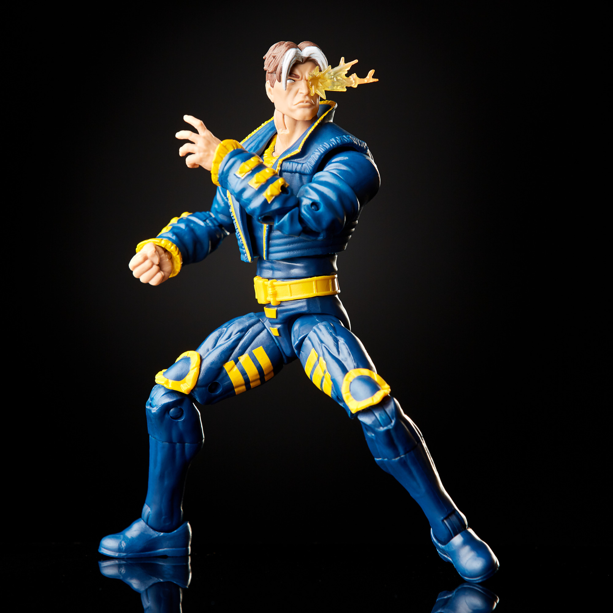 Action figure di un uomo in tuta blu e gialla, con raggio di energia dall'occhio. Sfondo nero.