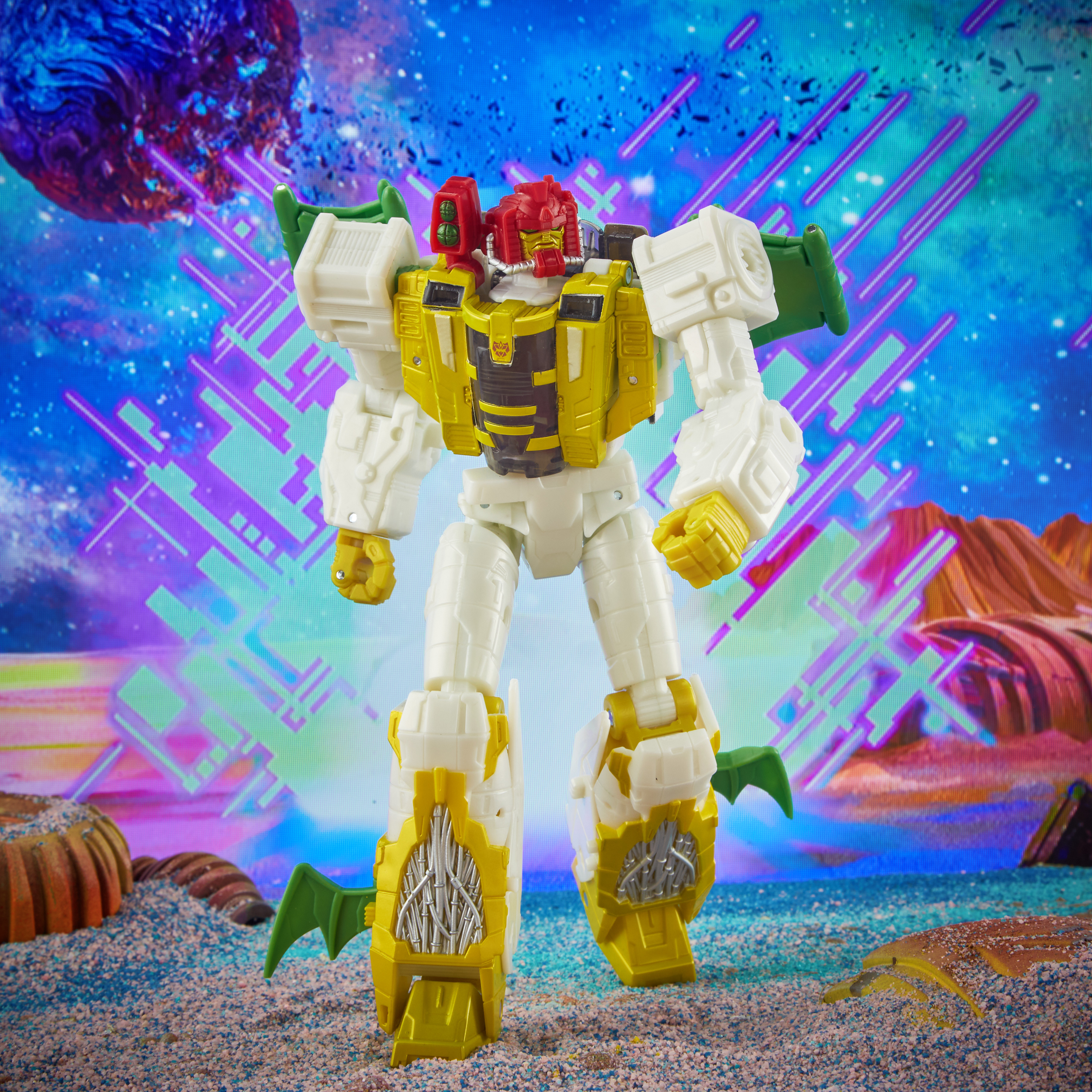 Giocattolo robot con testa rossa, petto giallo e arti bianchi. Su sabbia con sfondo spaziale colorato.