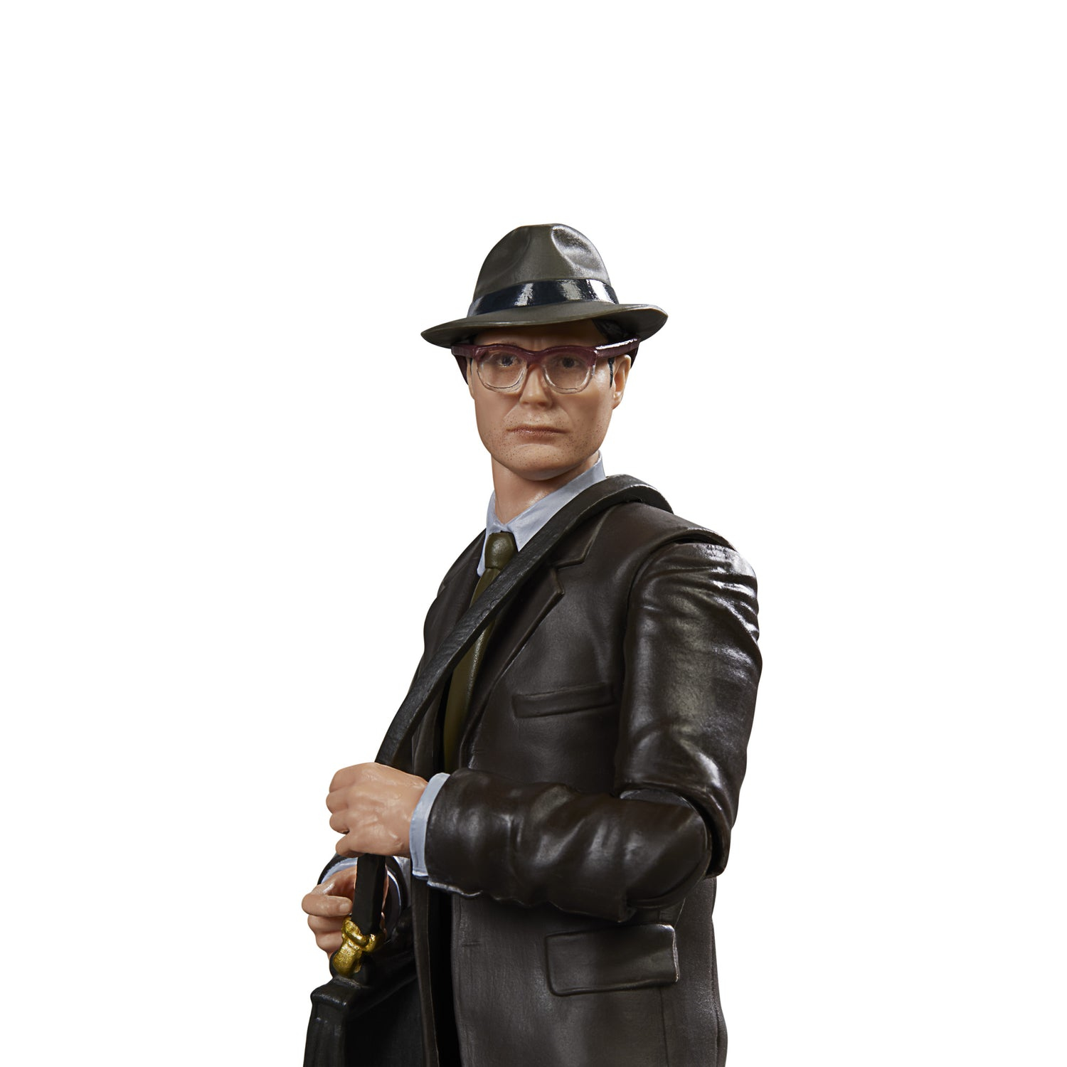Un uomo in abito marrone, cappello e occhiali, tiene una valigetta. Ha una cravatta e una camicia azzurra. Lo sfondo è bianco.