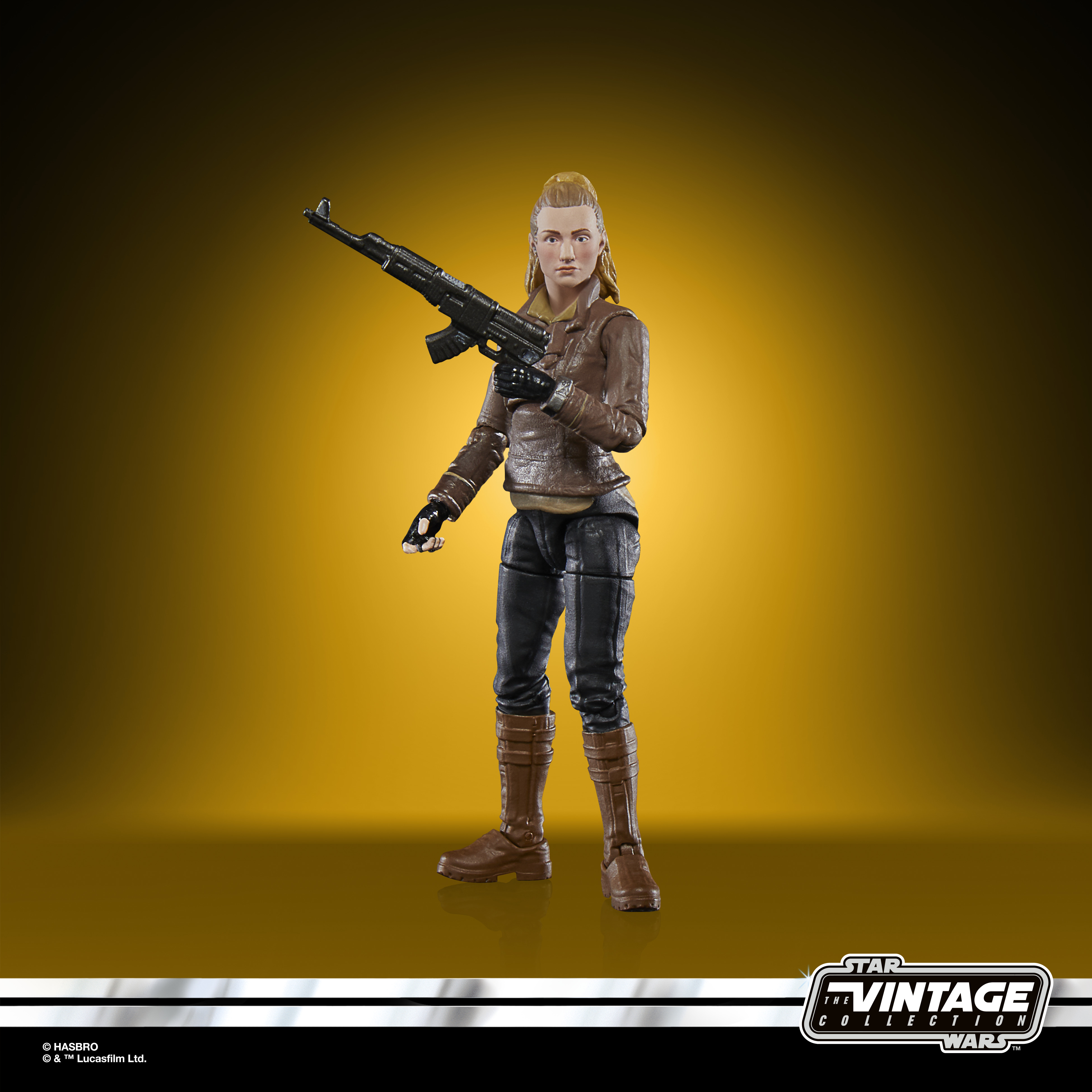 Figurka kobiety z czarnym karabinem. Nosi brązową kurtkę, czarne spodnie i brązowe buty.