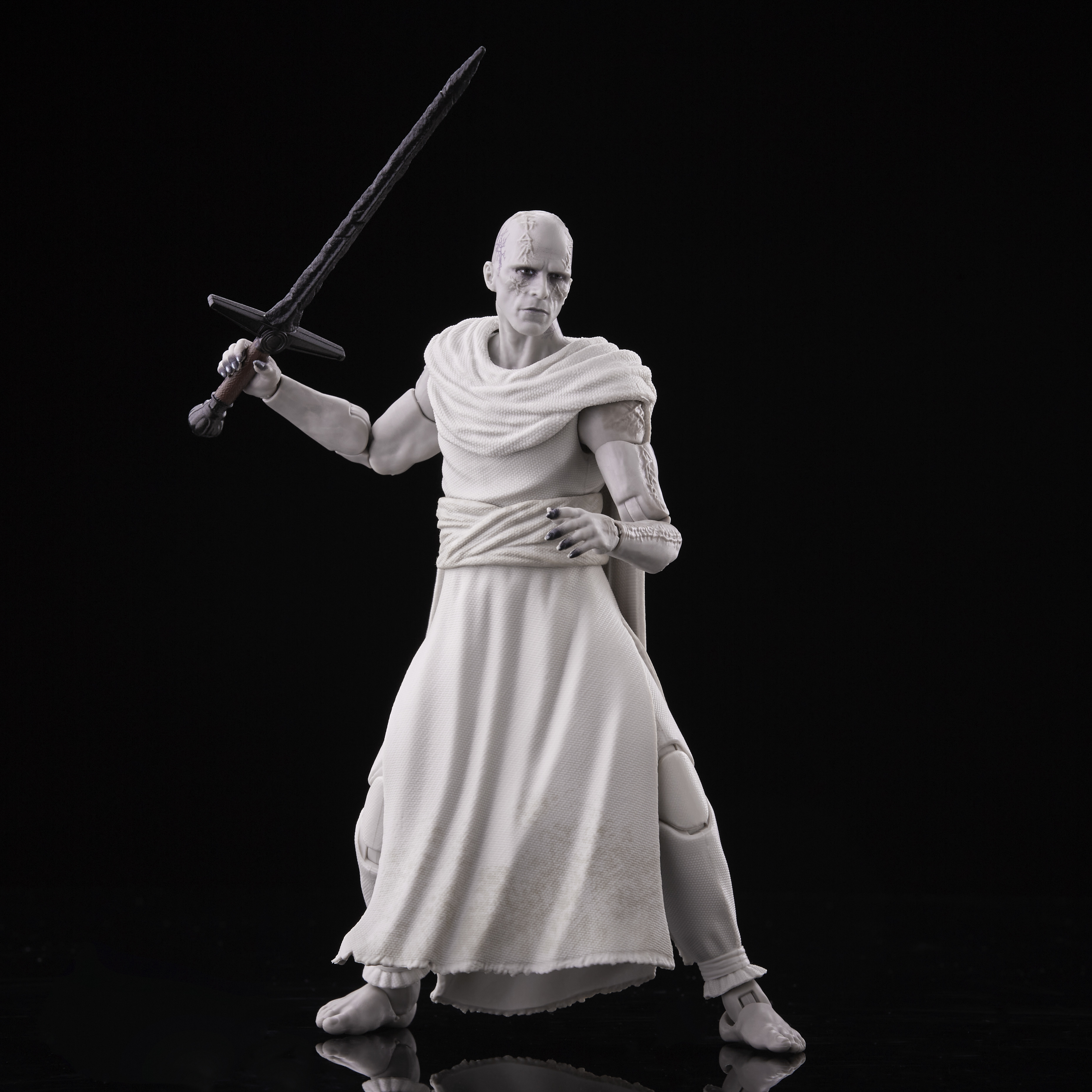 Biała postać trzyma miecz na czarnym tle. Postać ma na sobie białe szaty i blizny na twarzy.