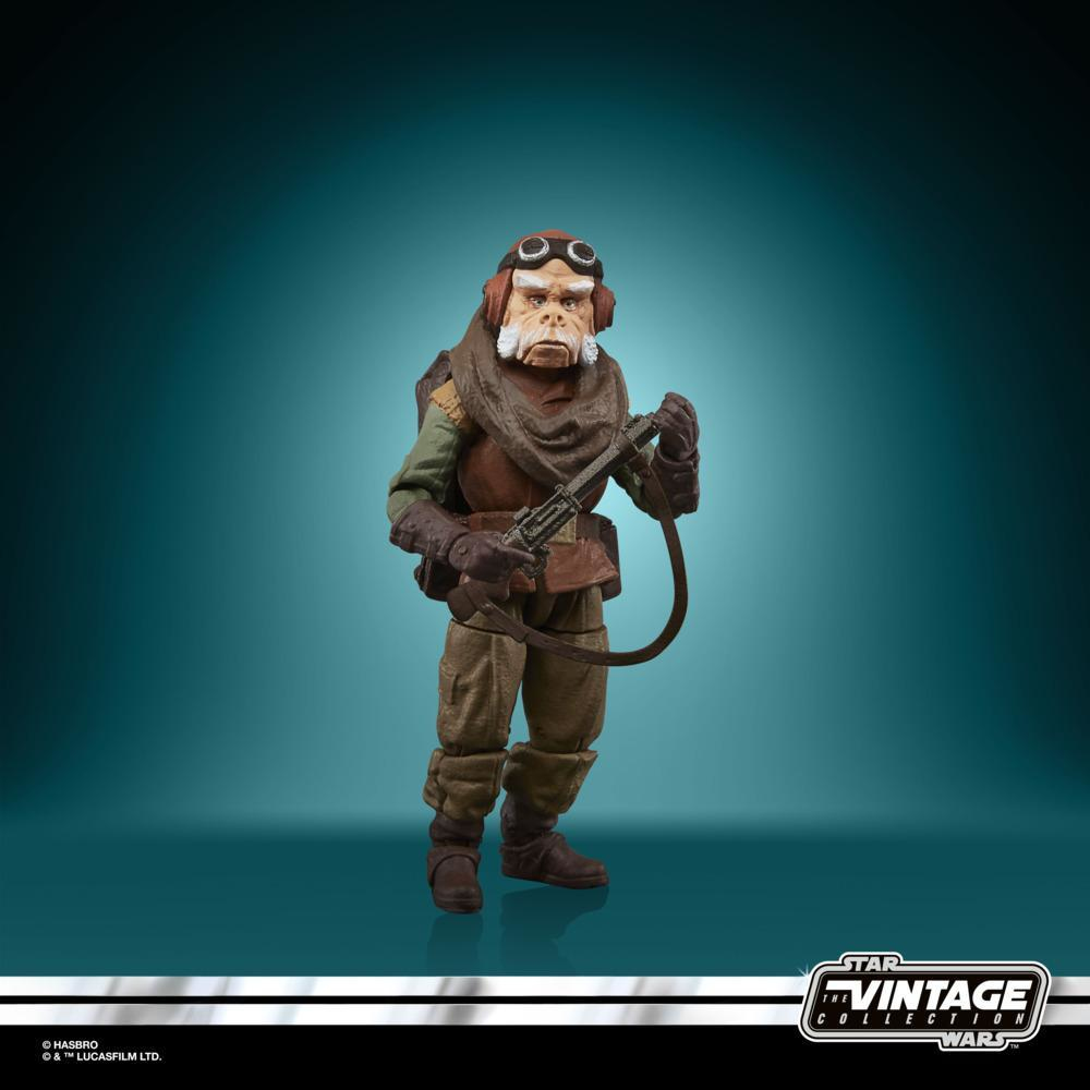 Una figura di Star Wars. È un umanoide con occhiali, che tiene un'arma. Indossa una sciarpa marrone e un completo verde e marrone.