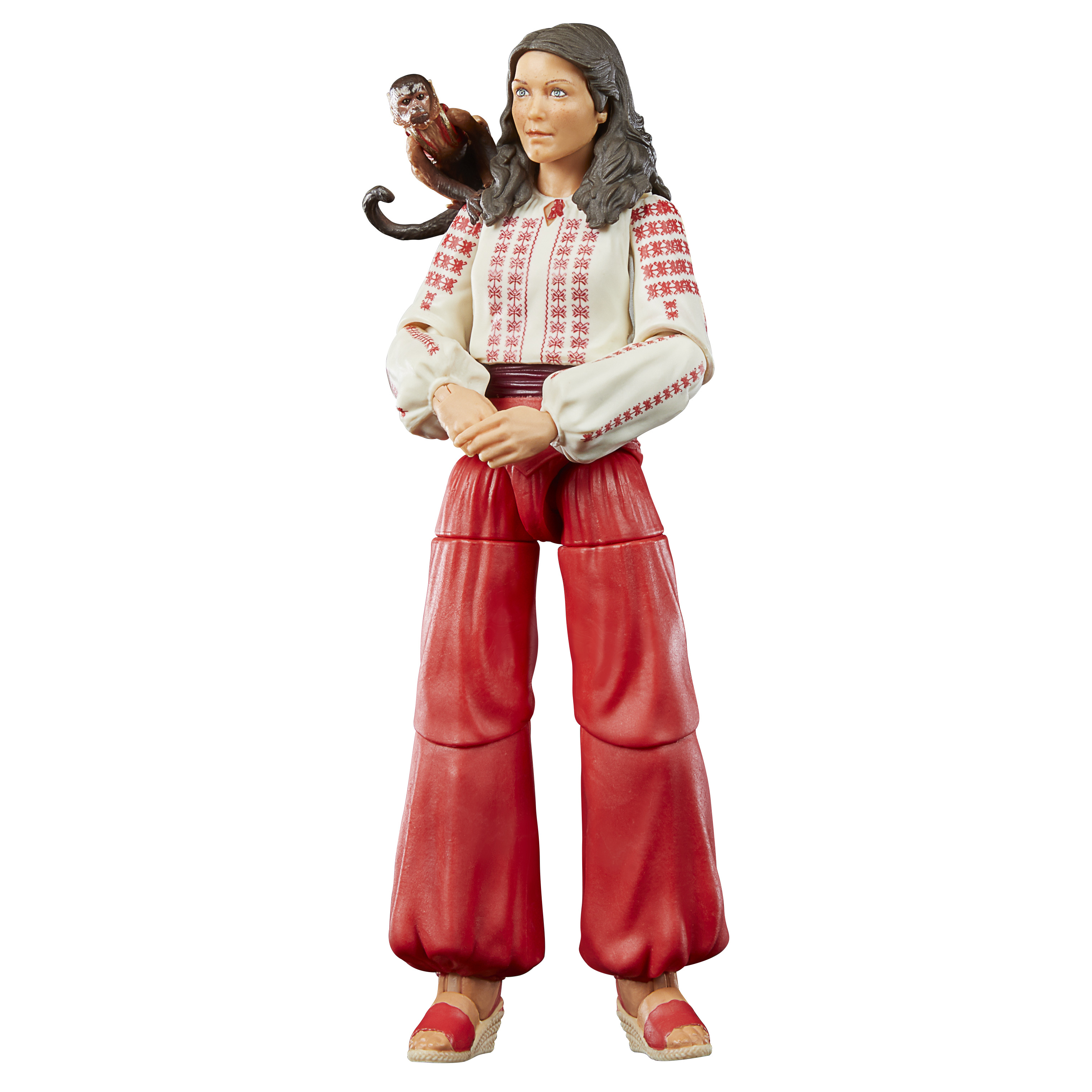 Una statuina di donna con una scimmia sulla spalla. Indossa una camicetta bianca con ricami rossi e pantaloni rossi.