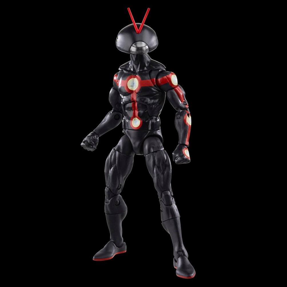 Una figura de acción negra con detalles rojos. Tiene un casco con antenas y círculos blancos brillantes en el cuerpo. La figura está contra un fondo negro.
