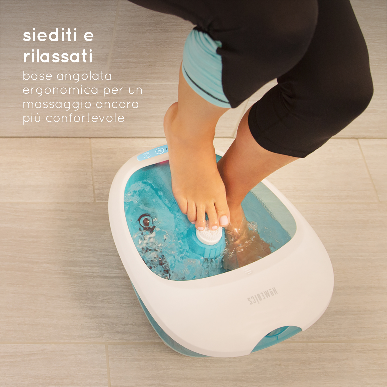 Personenfüße in einem Fußbad. Hellblaues Wasser in einem weiß-blauen Fußmassagegerät. Beine sind mit schwarzen Leggings bedeckt.