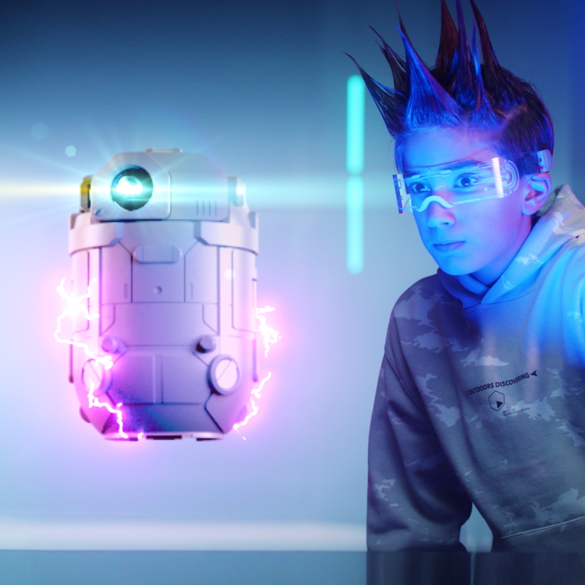 Un ragazzo con occhiali futuristici guarda un dispositivo fluttuante. Il dispositivo ha elettricità. Lo sfondo è blu.