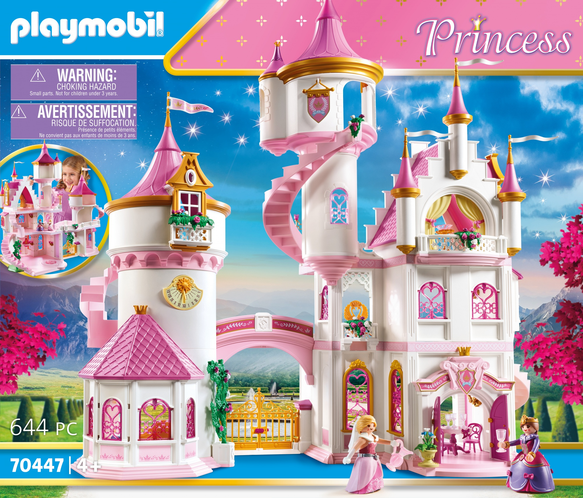 Ein Playmobil-Prinzessinnenschloss-Set mit rosa und weißen Türmen, Figuren und Details. Der Hintergrund zeigt Berge und blauen Himmel.