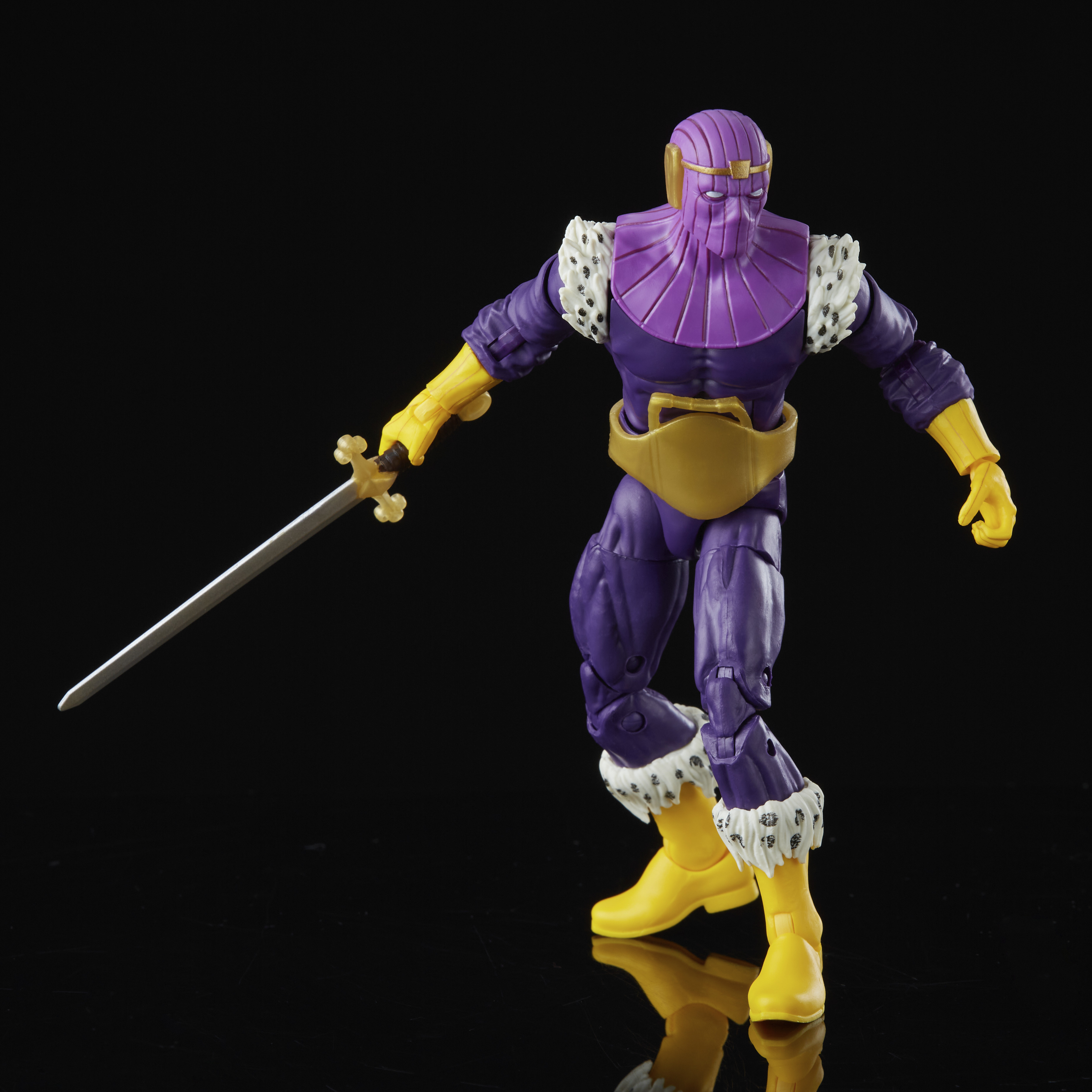 Action figure di un personaggio viola con guanti e stivali gialli, che tiene una spada, su sfondo nero.