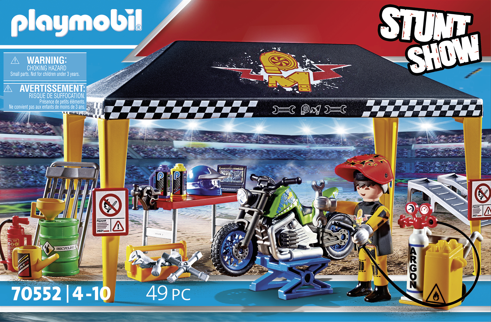 Scena pokazu kaskaderskiego Playmobil. Zawiera motocykl na podnośniku, mechanika i różne narzędzia, z czarno-białym szachownicowym zadaszeniem.