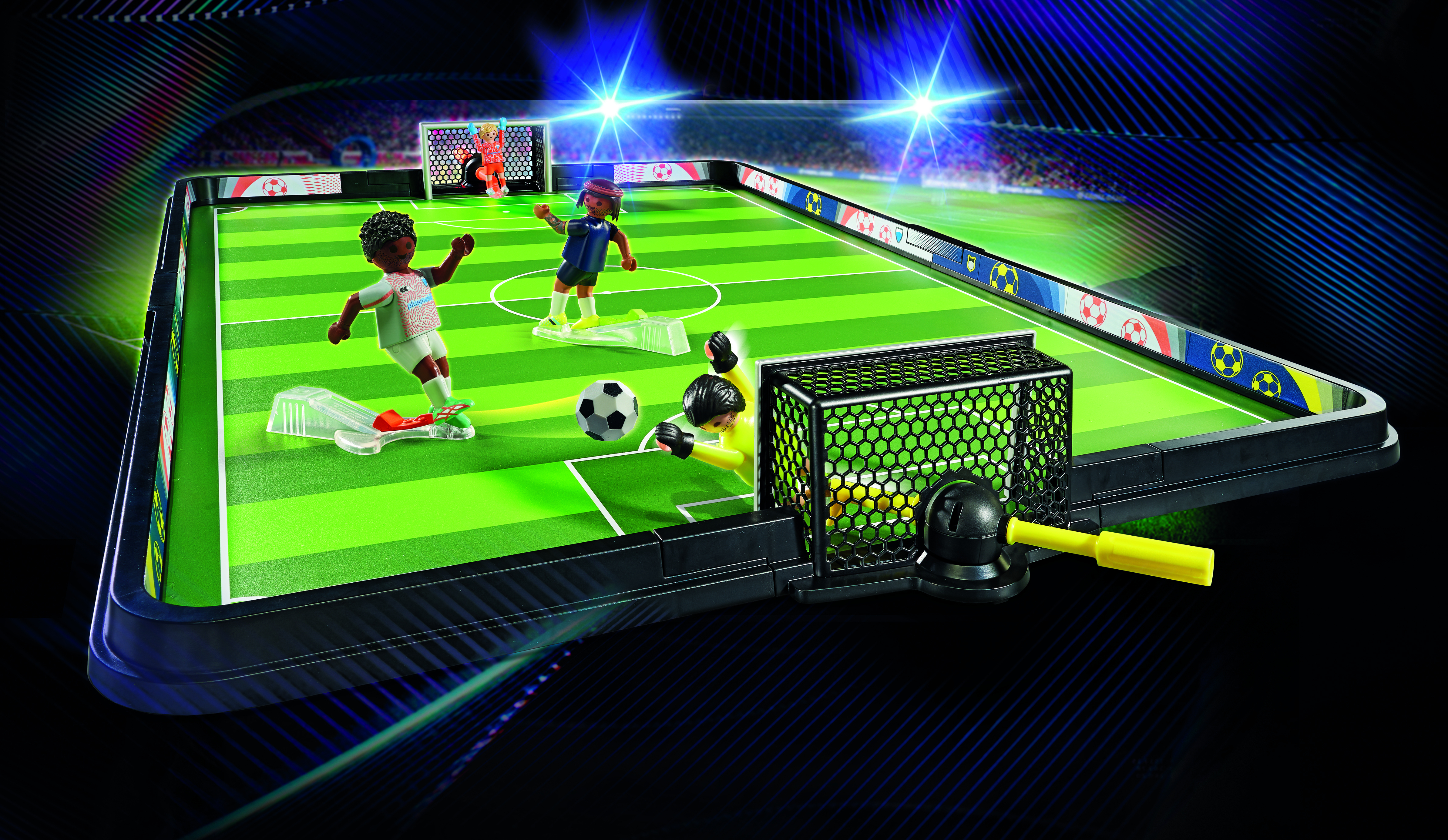 Zabawkowe boisko do piłki nożnej z zawodnikami, bramkarzem i piłką. Boisko jest zielone, tło granatowe.