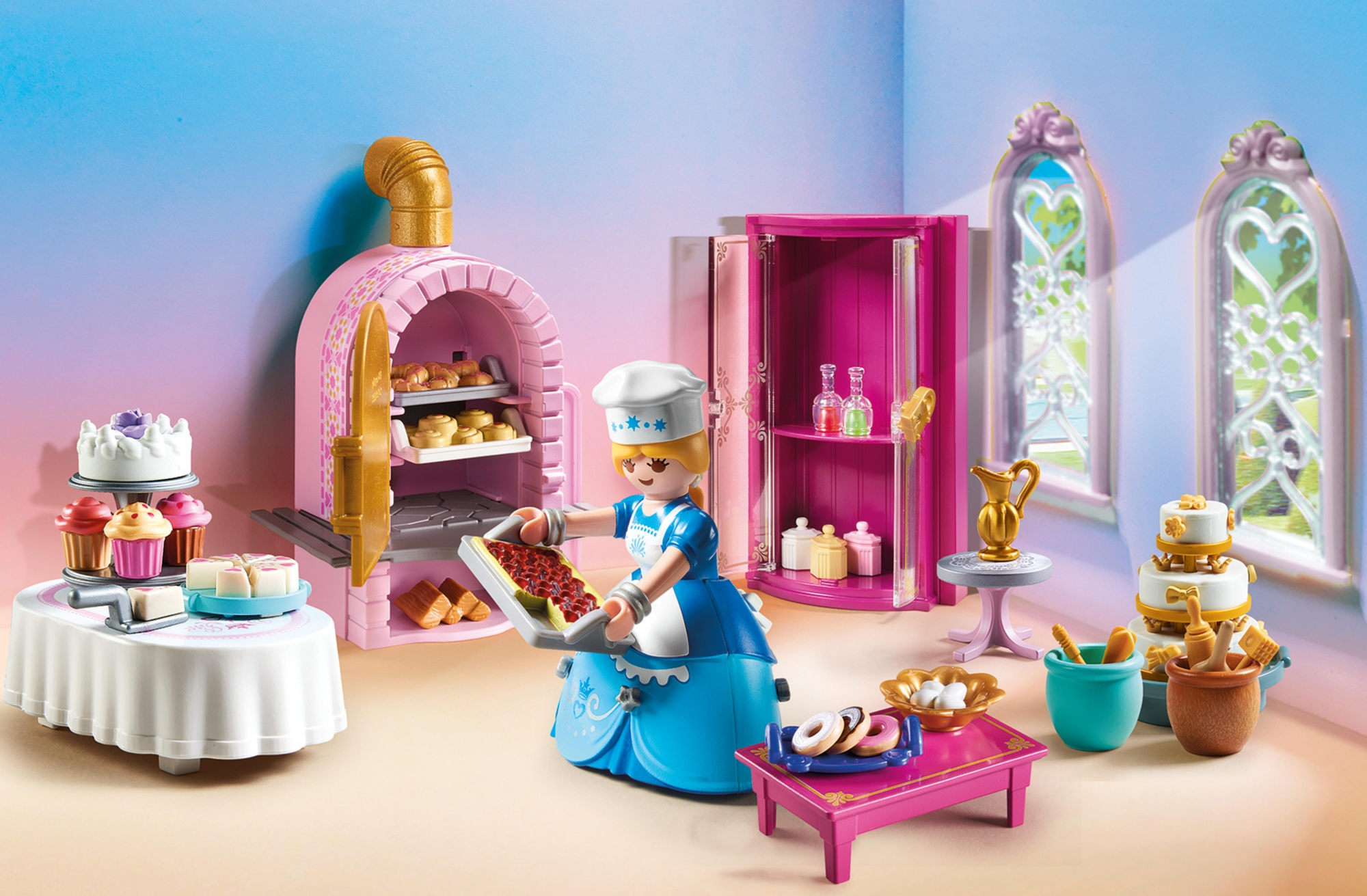 Una escena de panadería de juguete. Un panadero sostiene una bandeja de pasteles. Hay un horno, pasteles, donas y otros artículos de panadería.