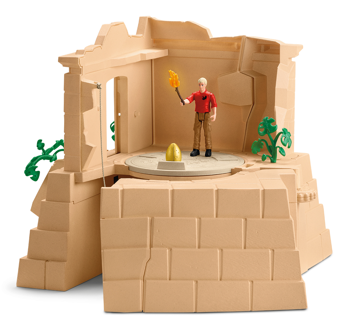 Speelgoedscène: een figuur met een fakkel staat bij een gouden ei. De set is een beige tempel met groene planten.