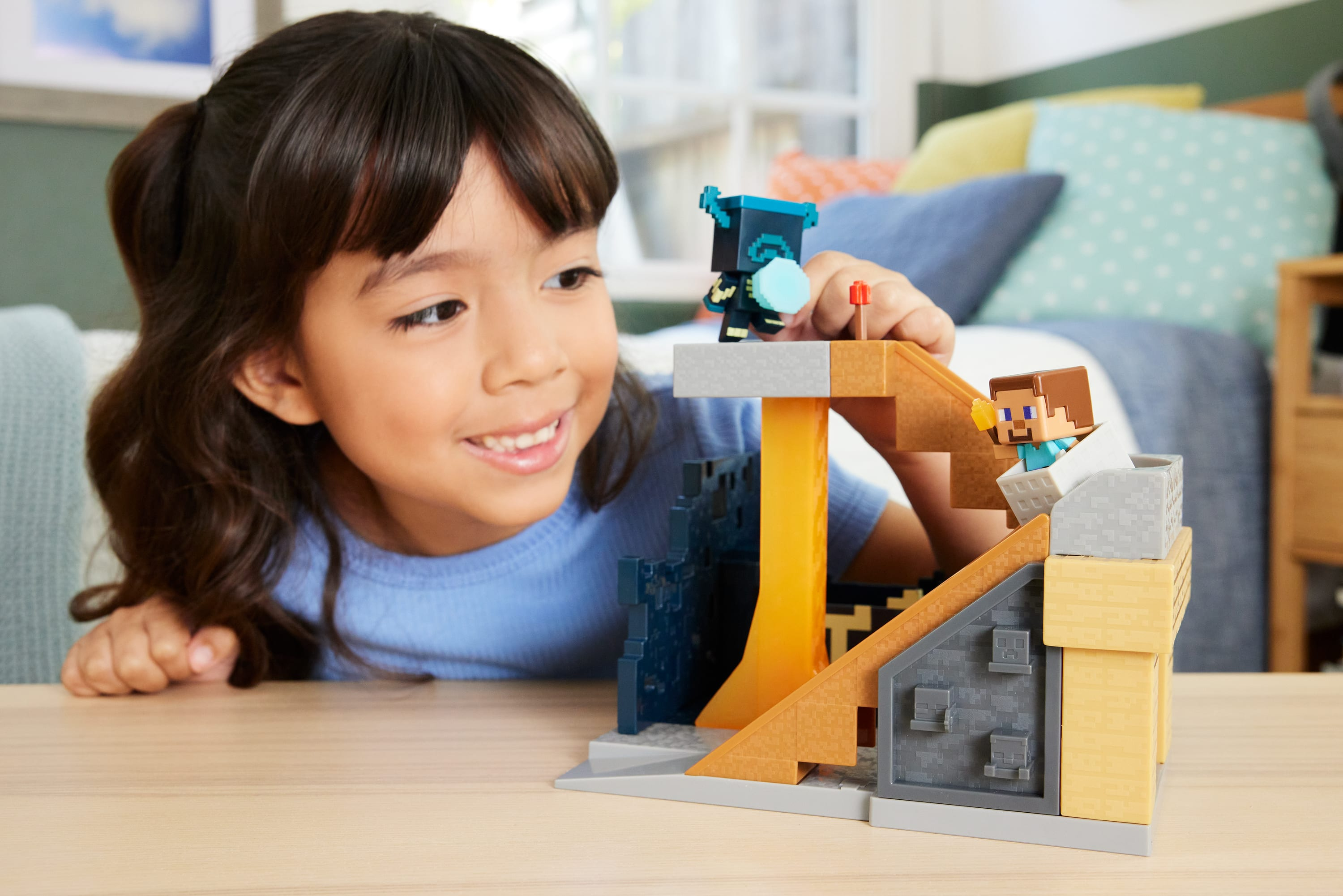 Dziewczyna uśmiecha się do zestawu do gry Minecraft z figurkami. Zestaw ma przepływ lawy i postacie.