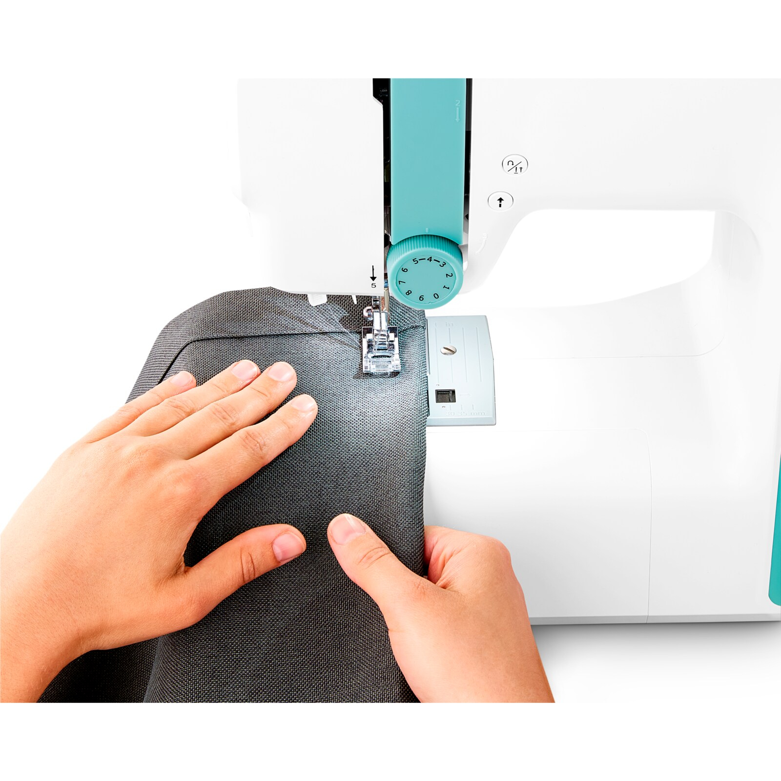 Dłonie prowadzą materiał pod igłą maszyny do szycia. Maszyna jest biała i turkusowa.