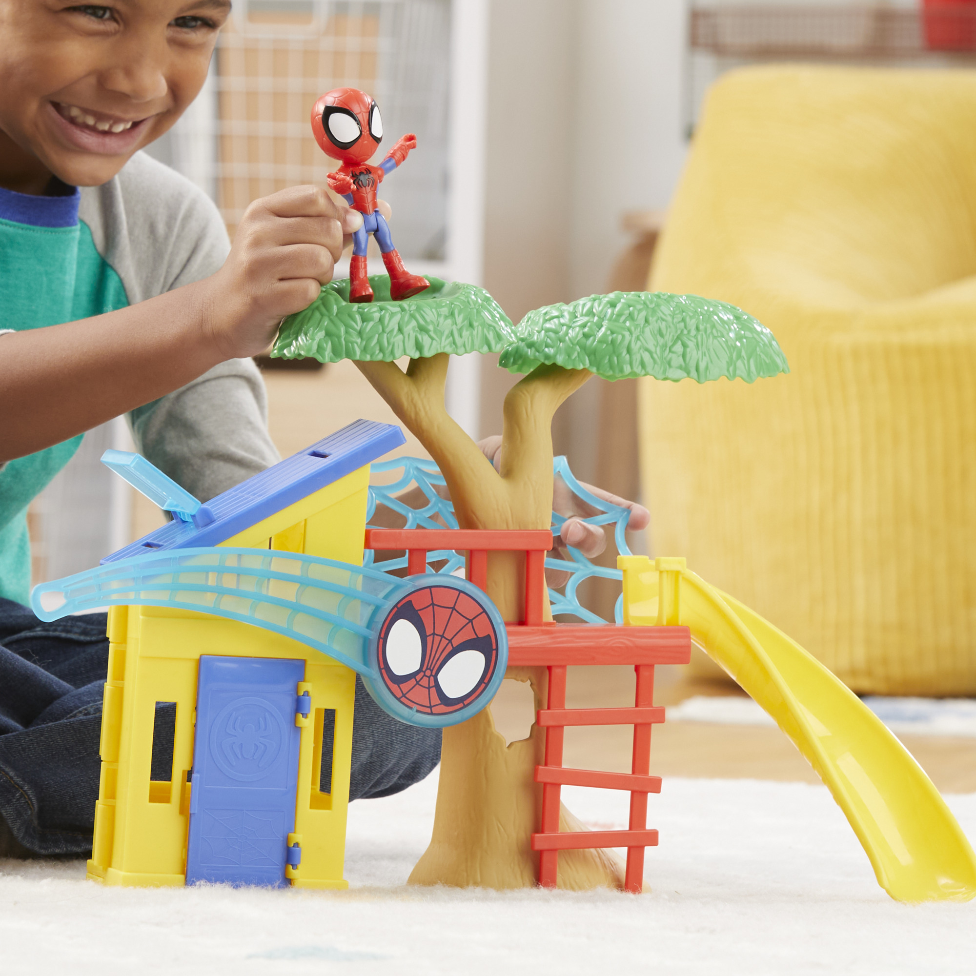 Un bambino gioca con un set di giocattoli di Spider-Man. Include un edificio giallo, una casa sull'albero e una statuetta di Spider-Man.