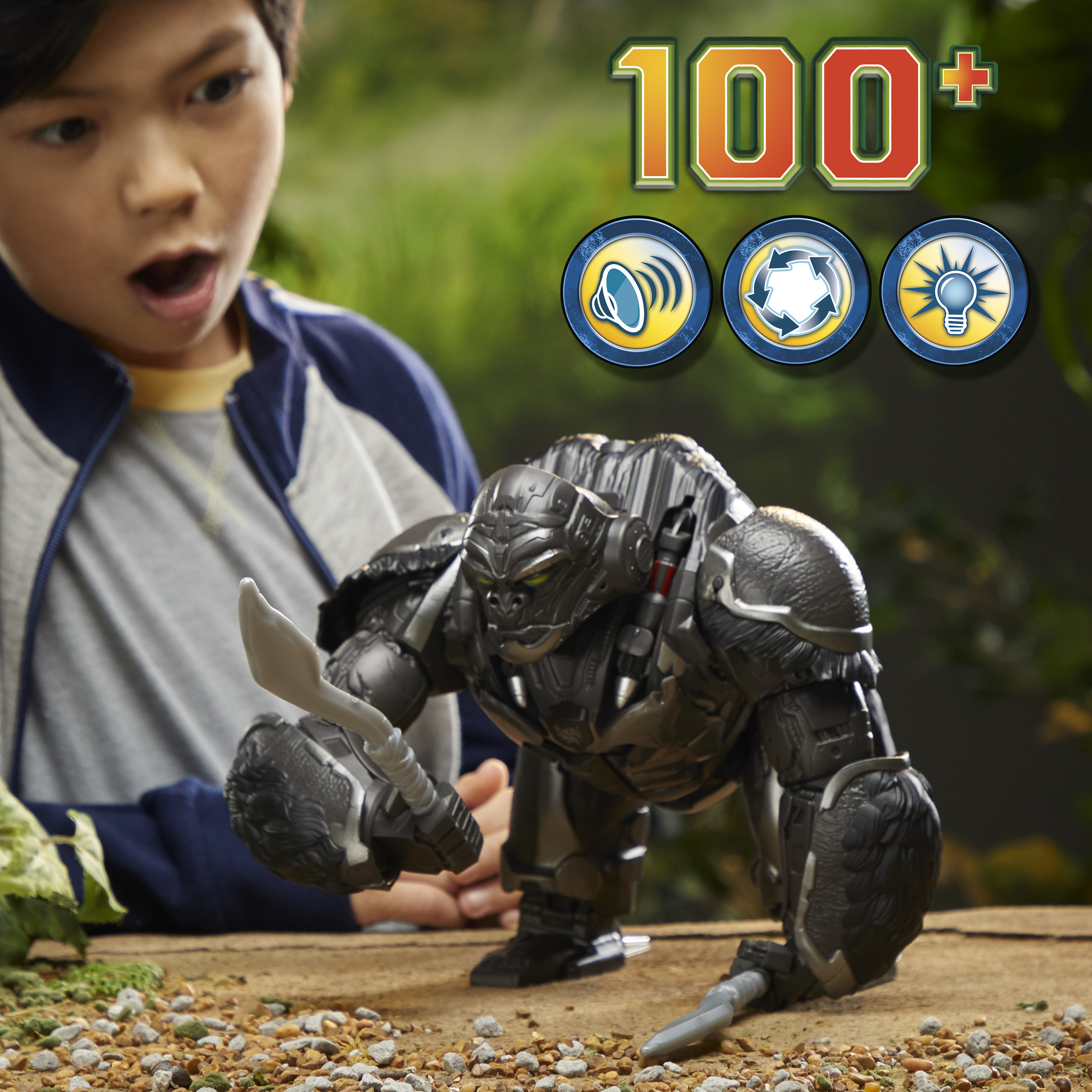 Chłopiec patrzy na zabawkę goryla. Zabawka jest czarno-srebrna, trzyma broń. Tło jest zielone.