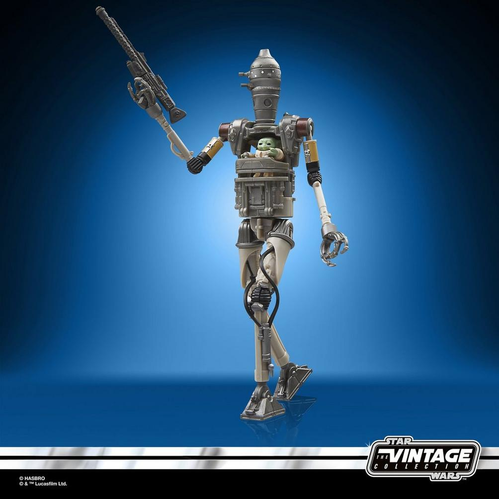 Figurka akcji Star Wars IG-11 z blasterem i figurką Grogu. Tło jest niebieskie z logo Vintage Collection.