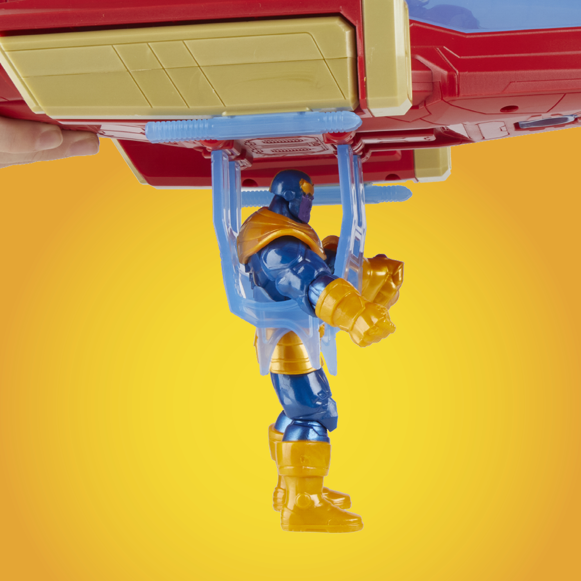 Figurka Thanosa wisi na czerwono-żółtej zabawce. Tło to żółty gradient.