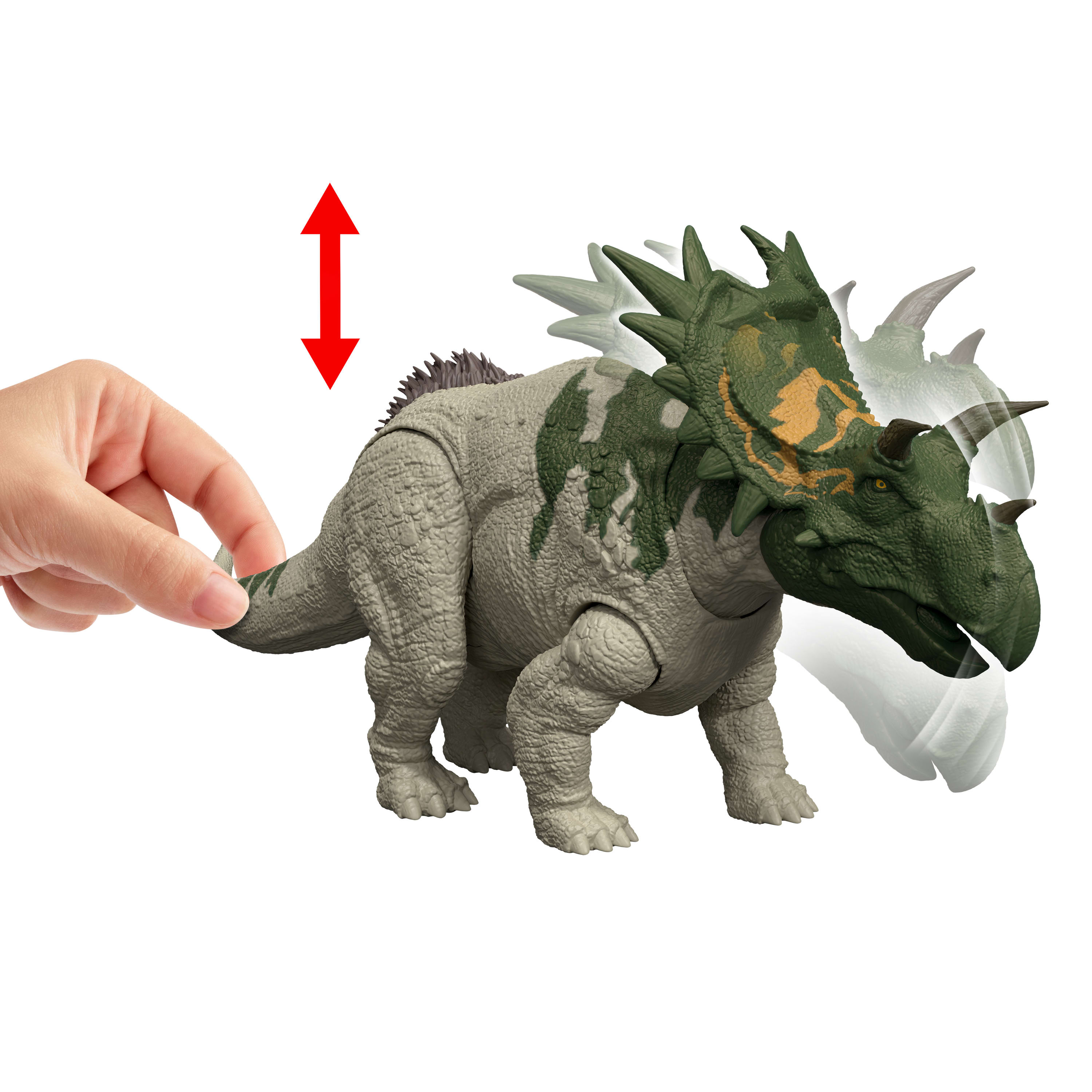 Zabawkowy dinozaur jest trzymany przez rękę. Dinozaur jest szary i zielony. Czerwona strzałka znajduje się powyżej.