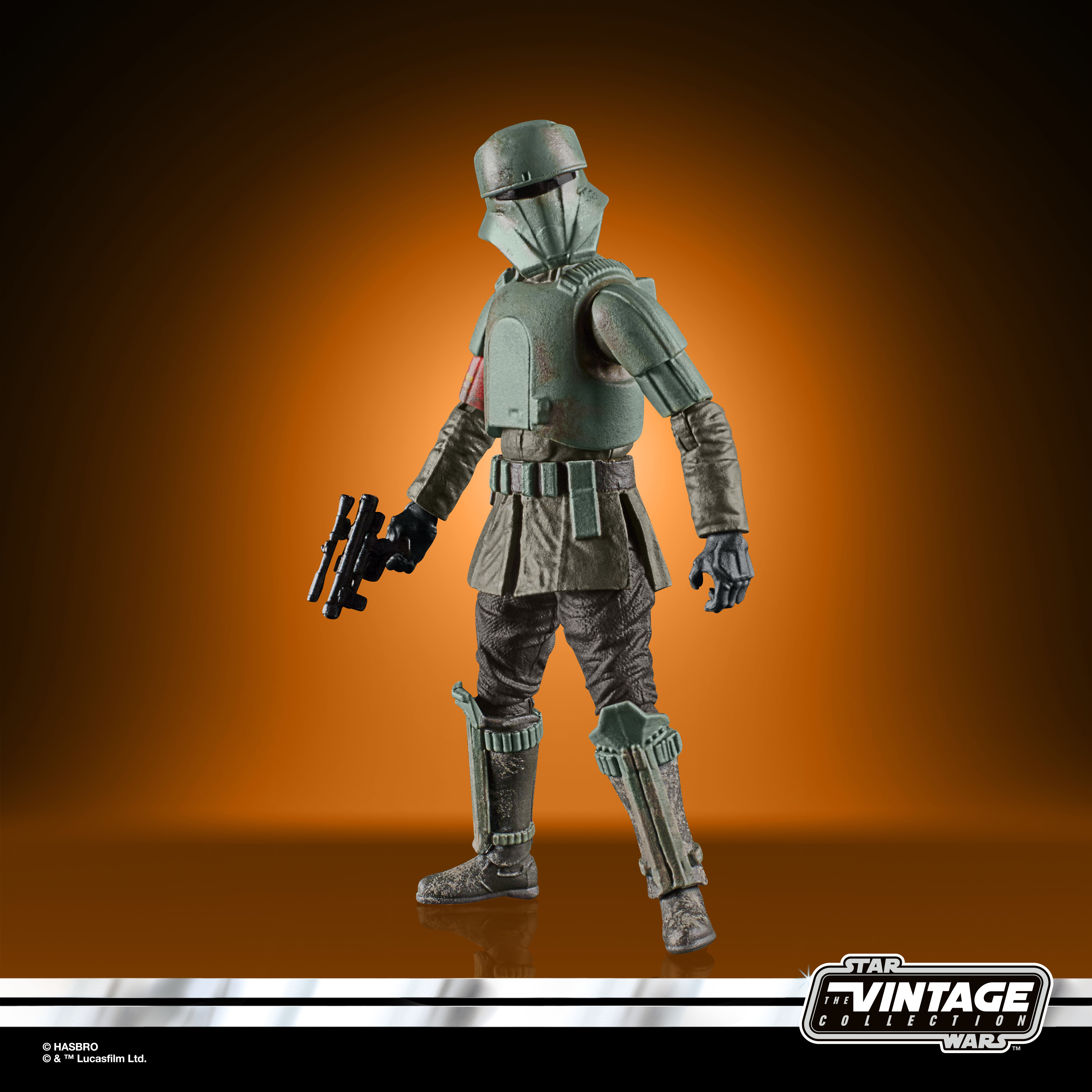 Una figura di Star Wars in piedi. Indossa un'armatura verde e tiene un blaster nero. Lo sfondo è arancione e marrone.