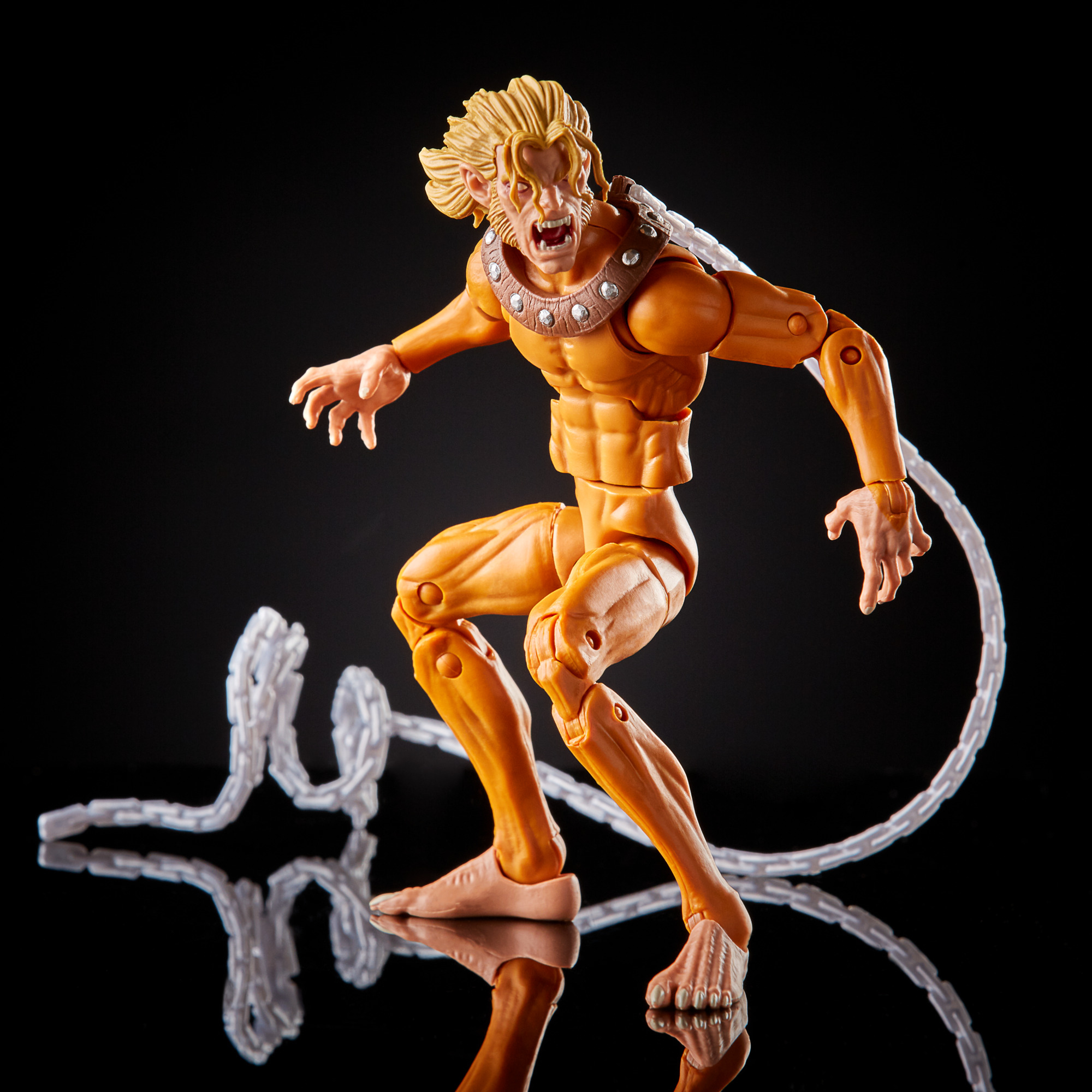 Action figure di un uomo dalla pelle gialla con artigli. Ha un accessorio a forma di catena e si trova su una superficie nera riflettente.