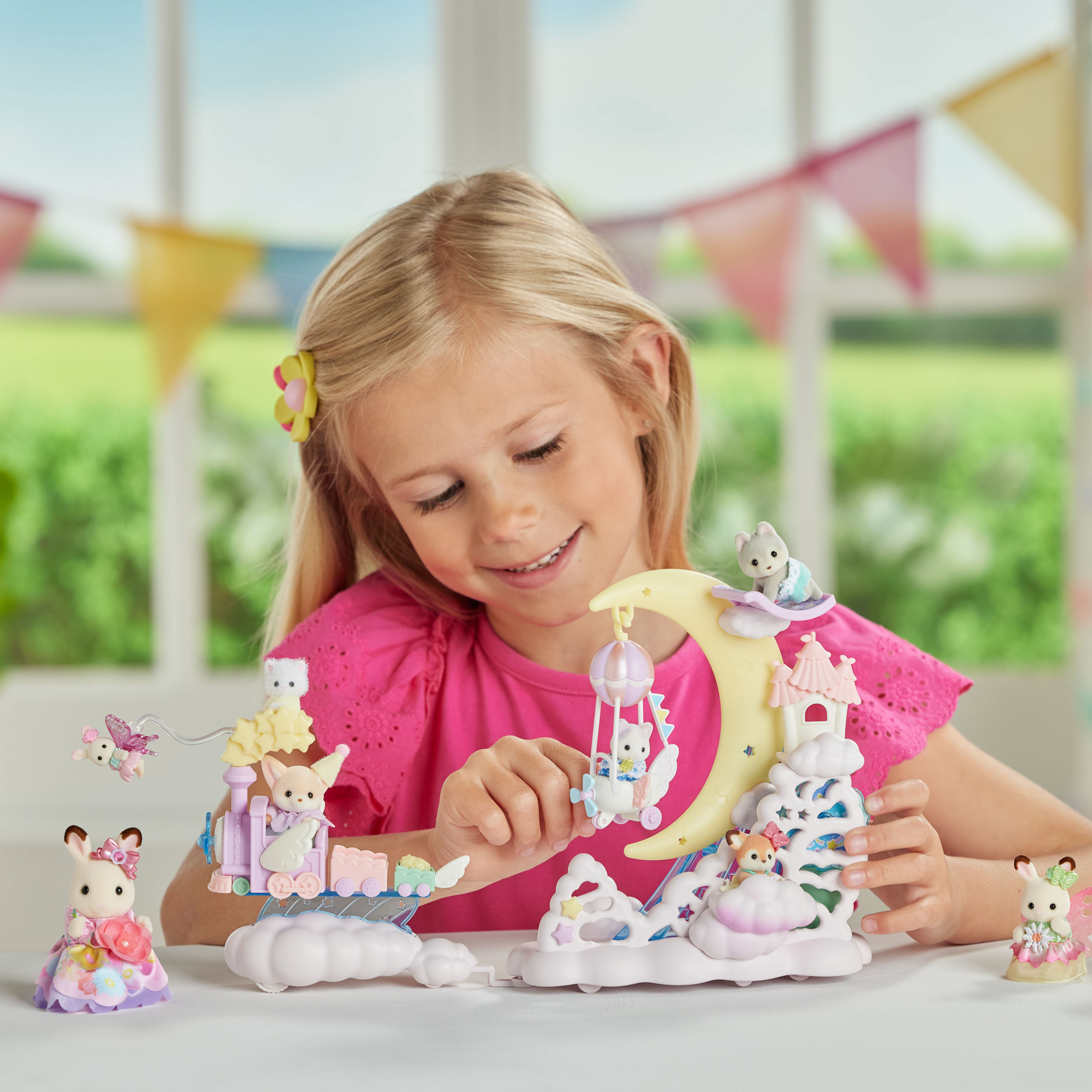Una niña juega con un juego de juguetes con figuras de conejos y una estructura en forma de luna sobre una mesa blanca.