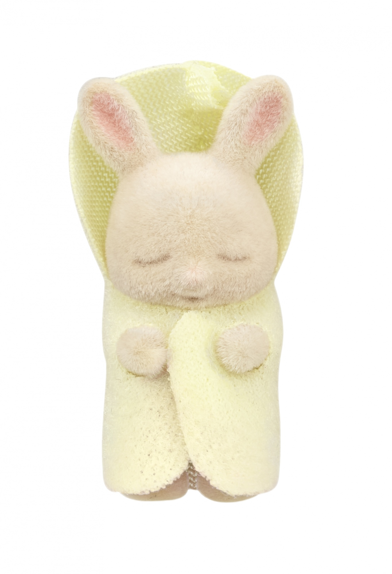 Un juguete de conejo color crema con una manta con capucha amarilla. Tiene los ojos cerrados y orejas rosadas. El fondo es blanco.