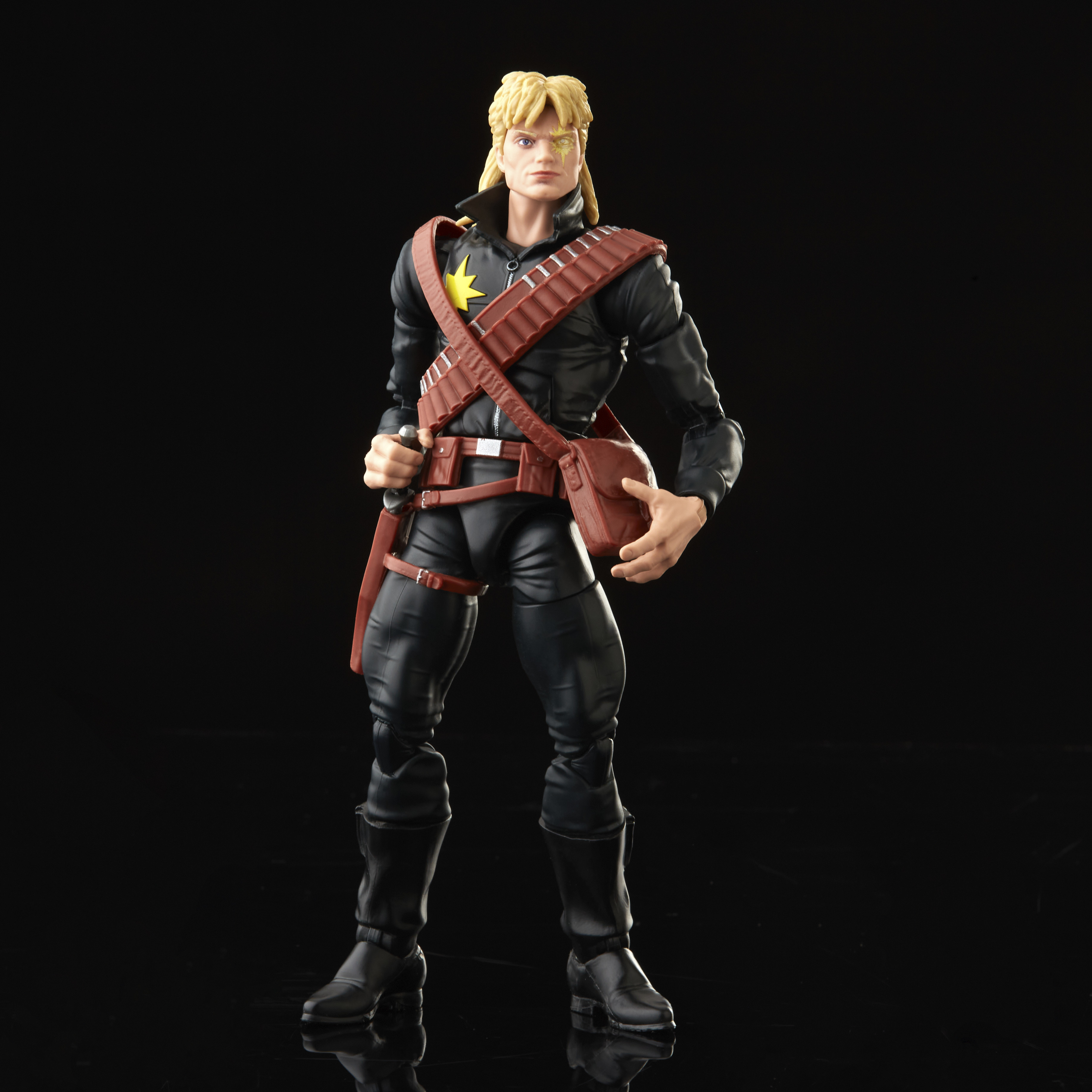 Un action figure maschile con abito nero, capelli biondi e cintura marrone. Lo sfondo è nero.