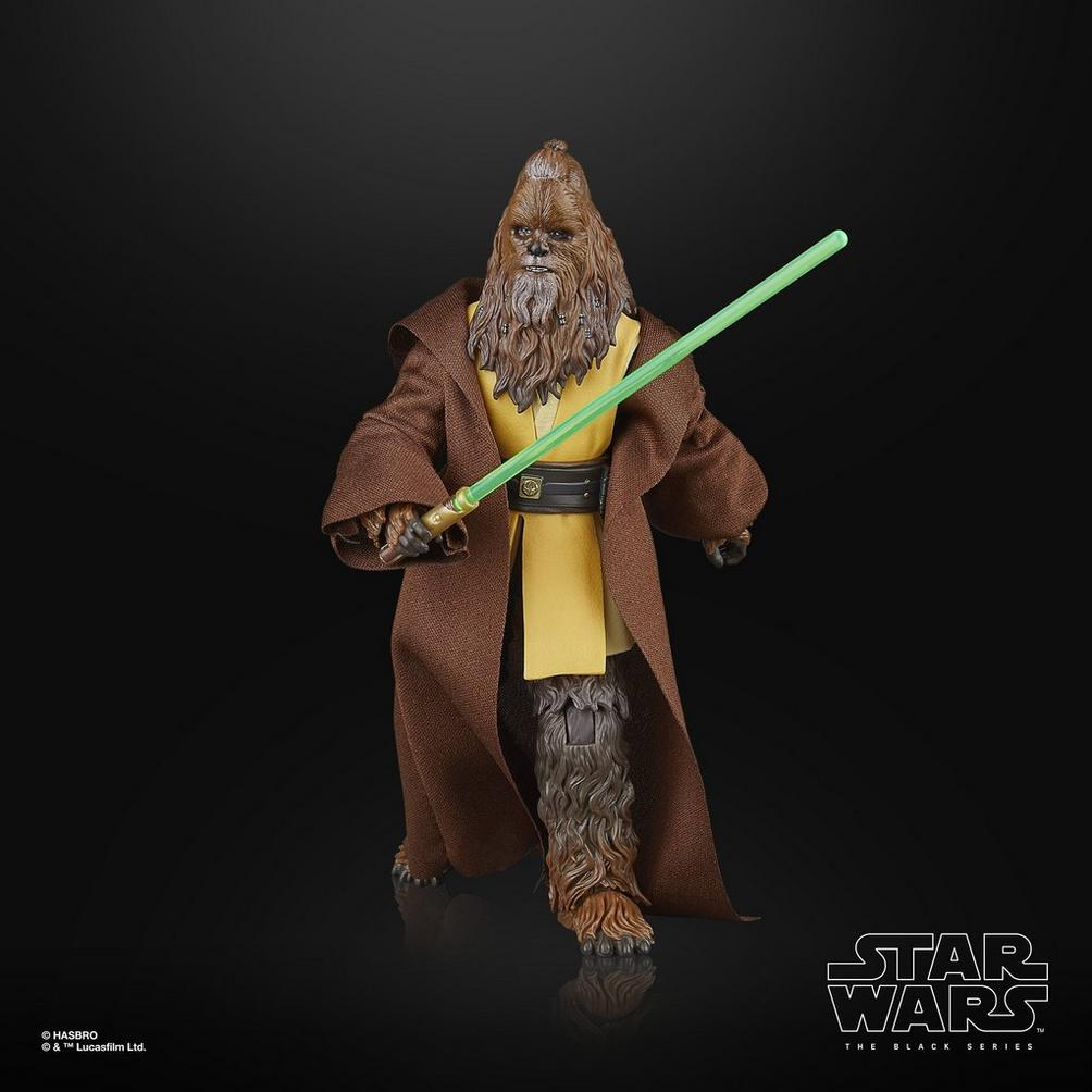 Una figura di Chewbacca in una veste marrone che tiene una spada laser verde. Su sfondo nero. Logo di Star Wars visibile.