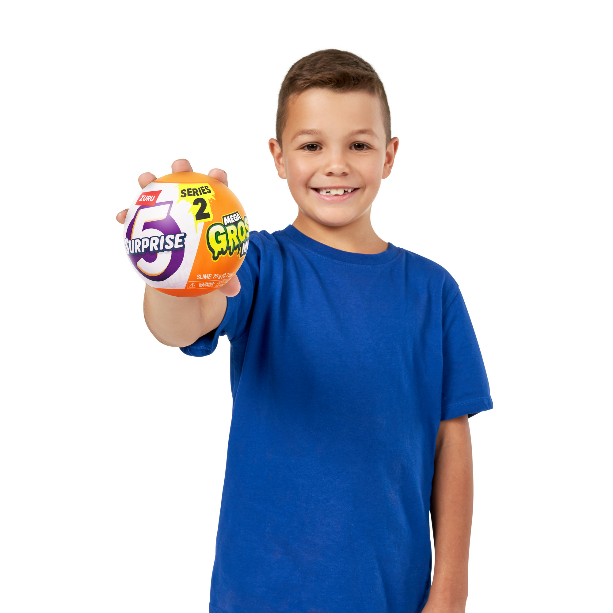 Ein Junge hält einen bunten Ball mit der Aufschrift "Surprise 5" und "Mega Gross". Er trägt ein blaues Hemd und lächelt.