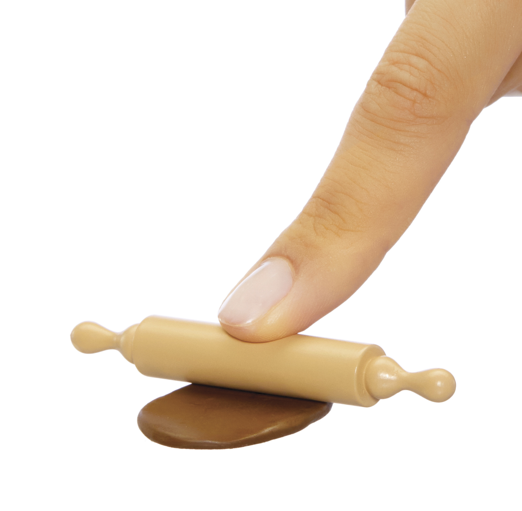 Ręka wałkuje brązowe ciasto beżowym wałkiem na białym tle.