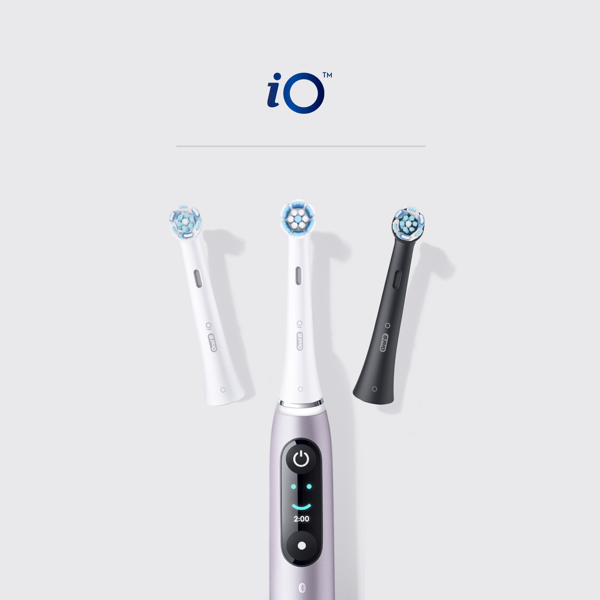 Un cepillo de dientes eléctrico con tres cabezales. Un mango morado está en el centro con una pantalla. El logotipo 'iO' es visible.