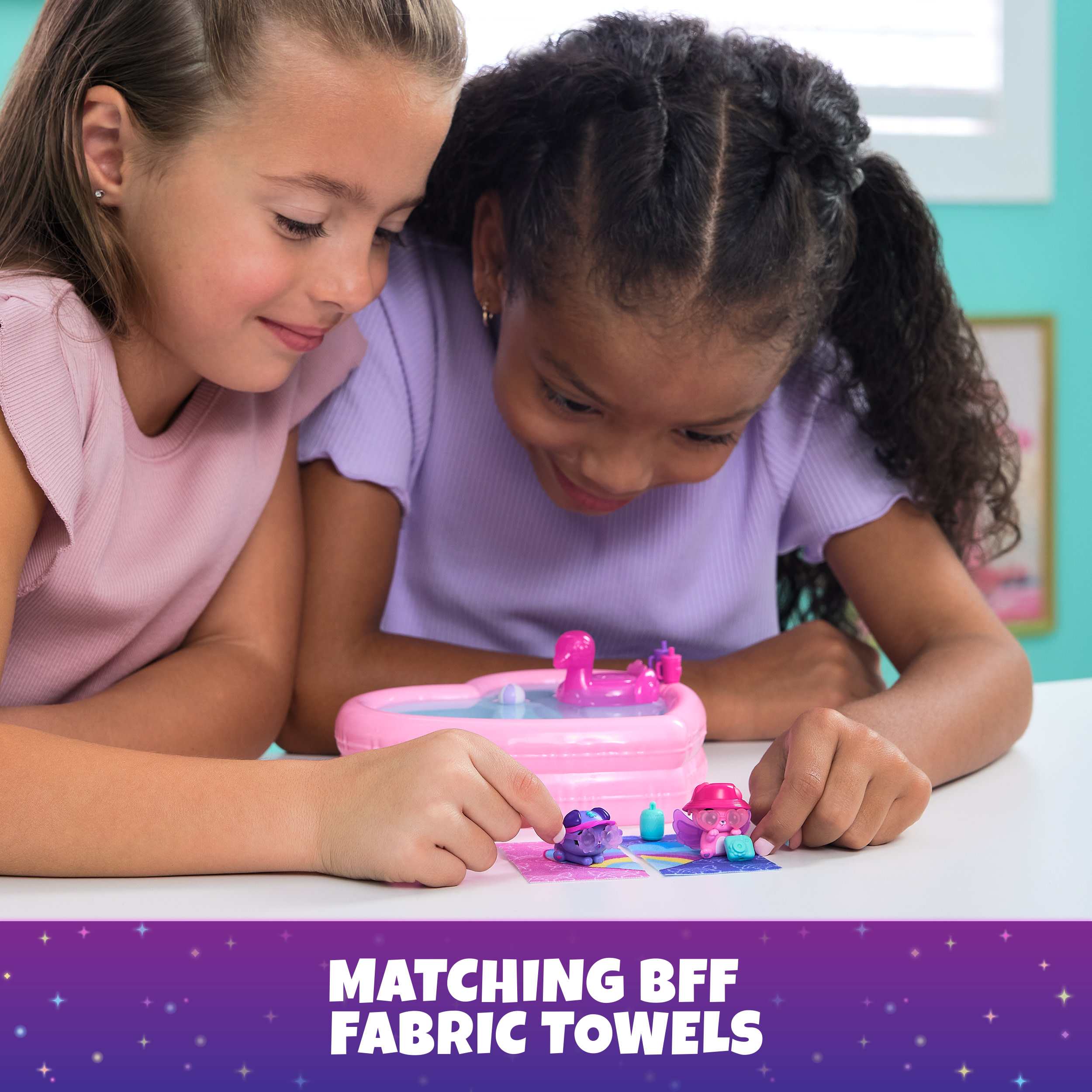 Zwei Mädchen spielen mit Spielfiguren und einem rosa Pool. Ein Banner zeigt 'Matching BFF Fabric Towels'.