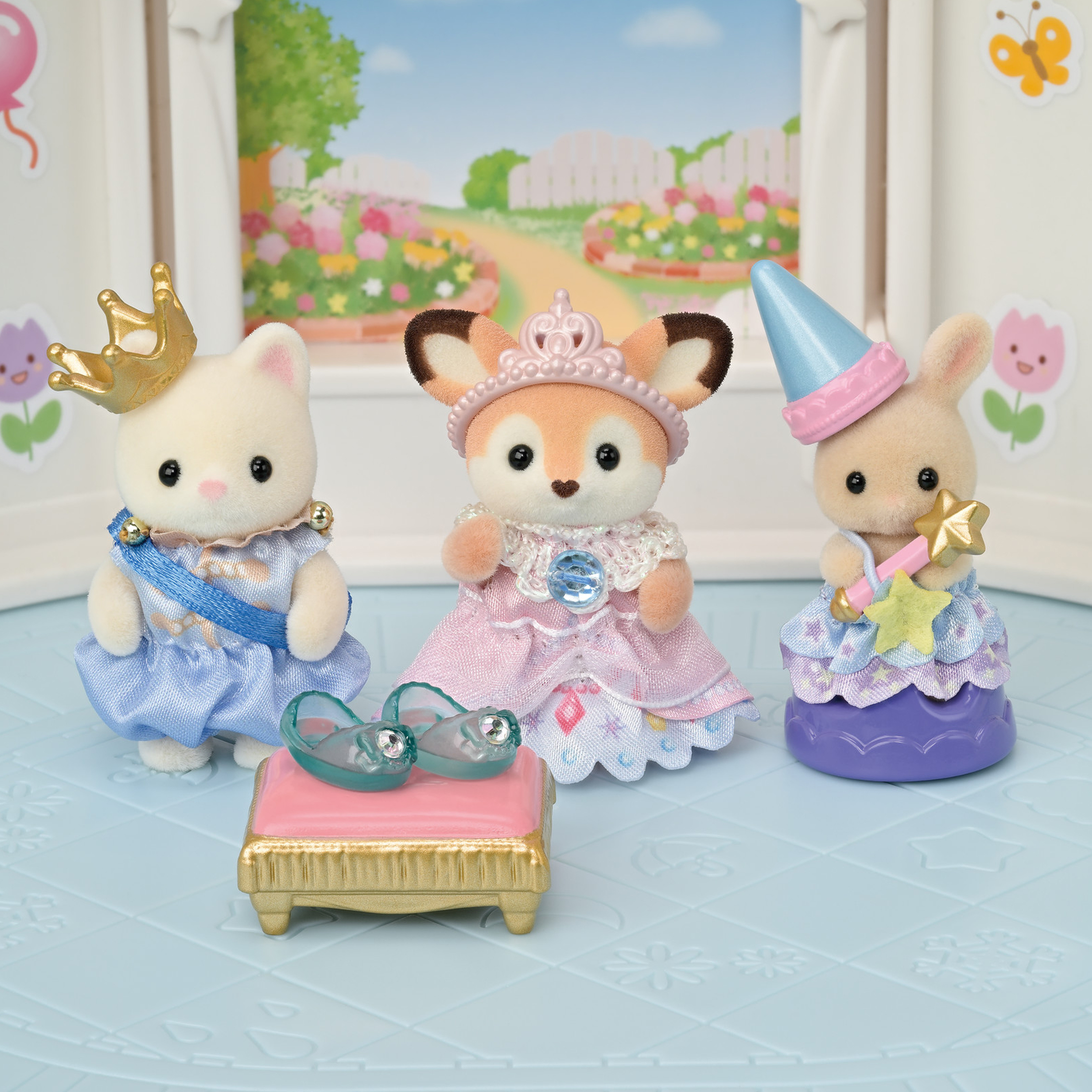 Tres figuras de animales con atuendo de princesa están sobre una superficie azul. Una pequeña cama rosa con zapatos está al frente.