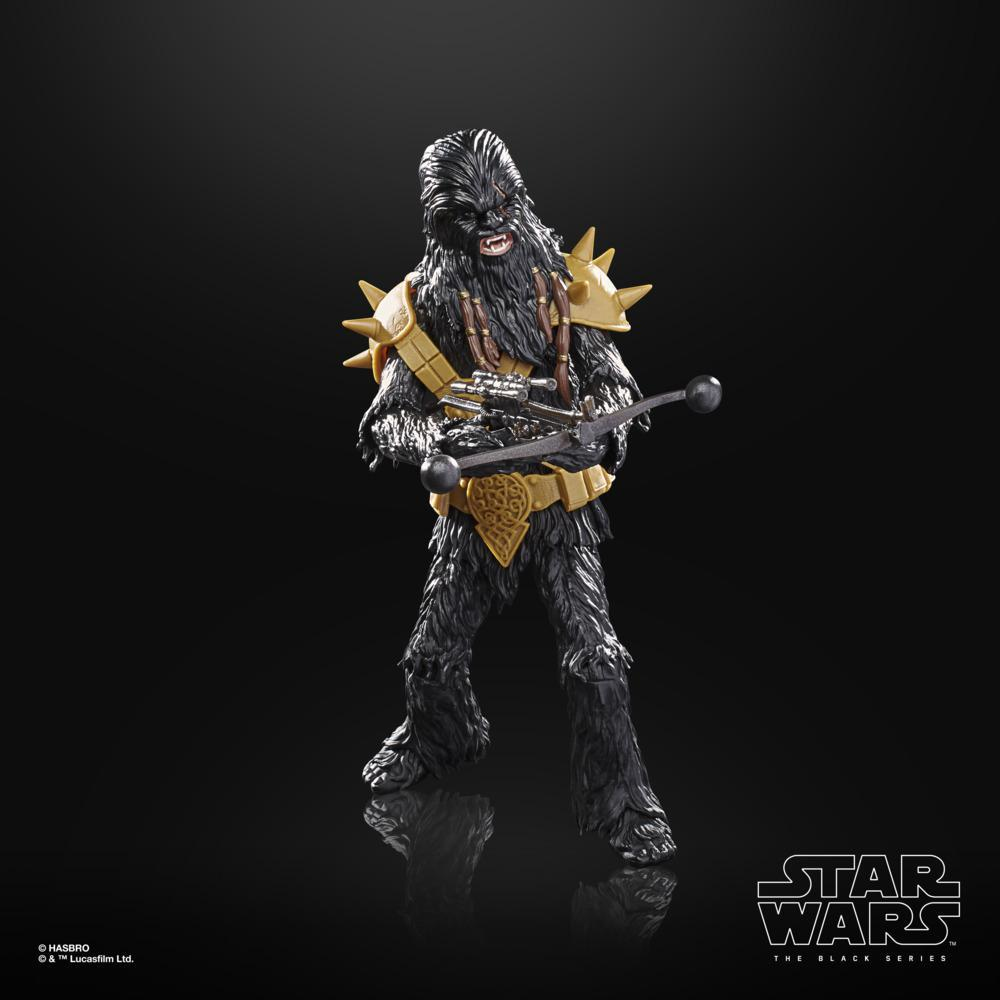 Action figure di Chewbacca di Star Wars, pelliccia nera, armatura dorata, tiene un'arma, su superficie riflettente, sfondo nero.