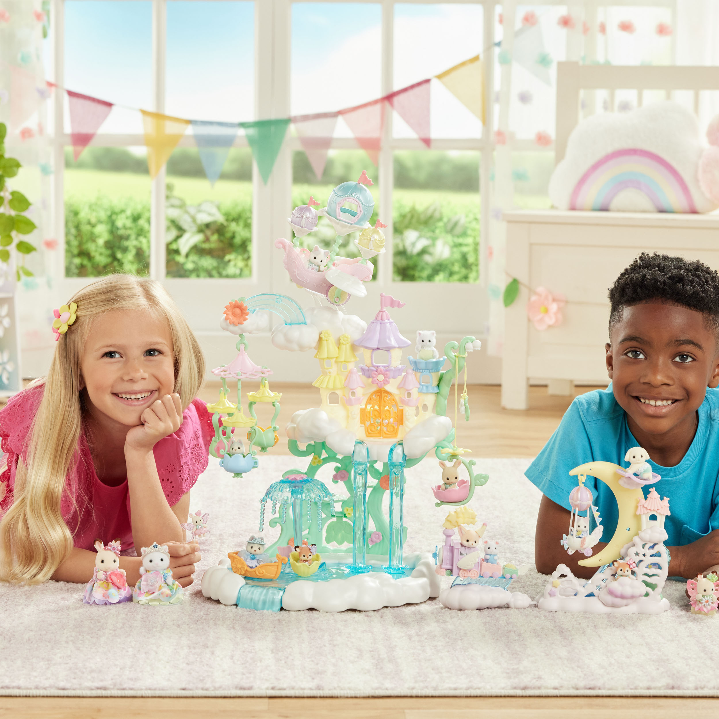 Dos niños con un castillo de juguete y figuras. Una niña rubia y un niño de piel oscura sonríen a la cámara.