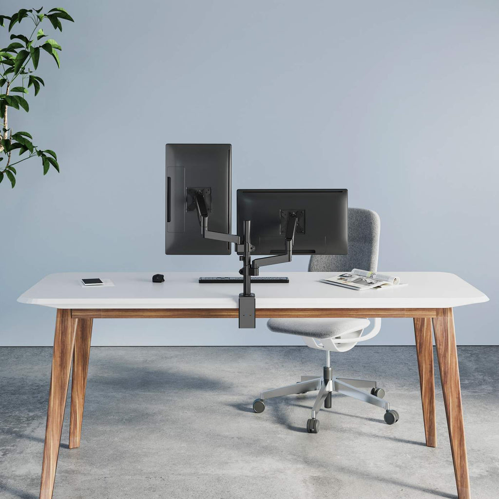 Nowoczesne biurko z dwoma monitorami przed niebieską ścianą. Szare krzesło za biurkiem. Po lewej stronie roślina.